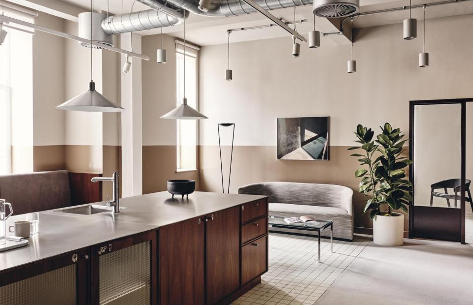 Contemporary office interior of Brock House featuring bespoke lighting, a modern kitchen, and stylish furnishings.