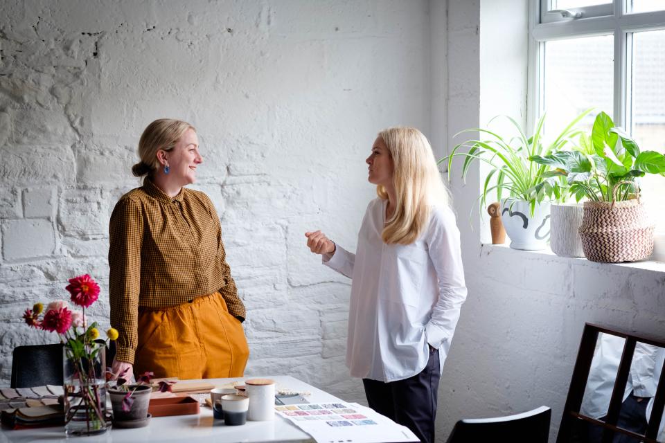 Rachel Withey and Sarah Dodsworth engaged in conversation at Ekho Studio, surrounded by artistic materials and plants.