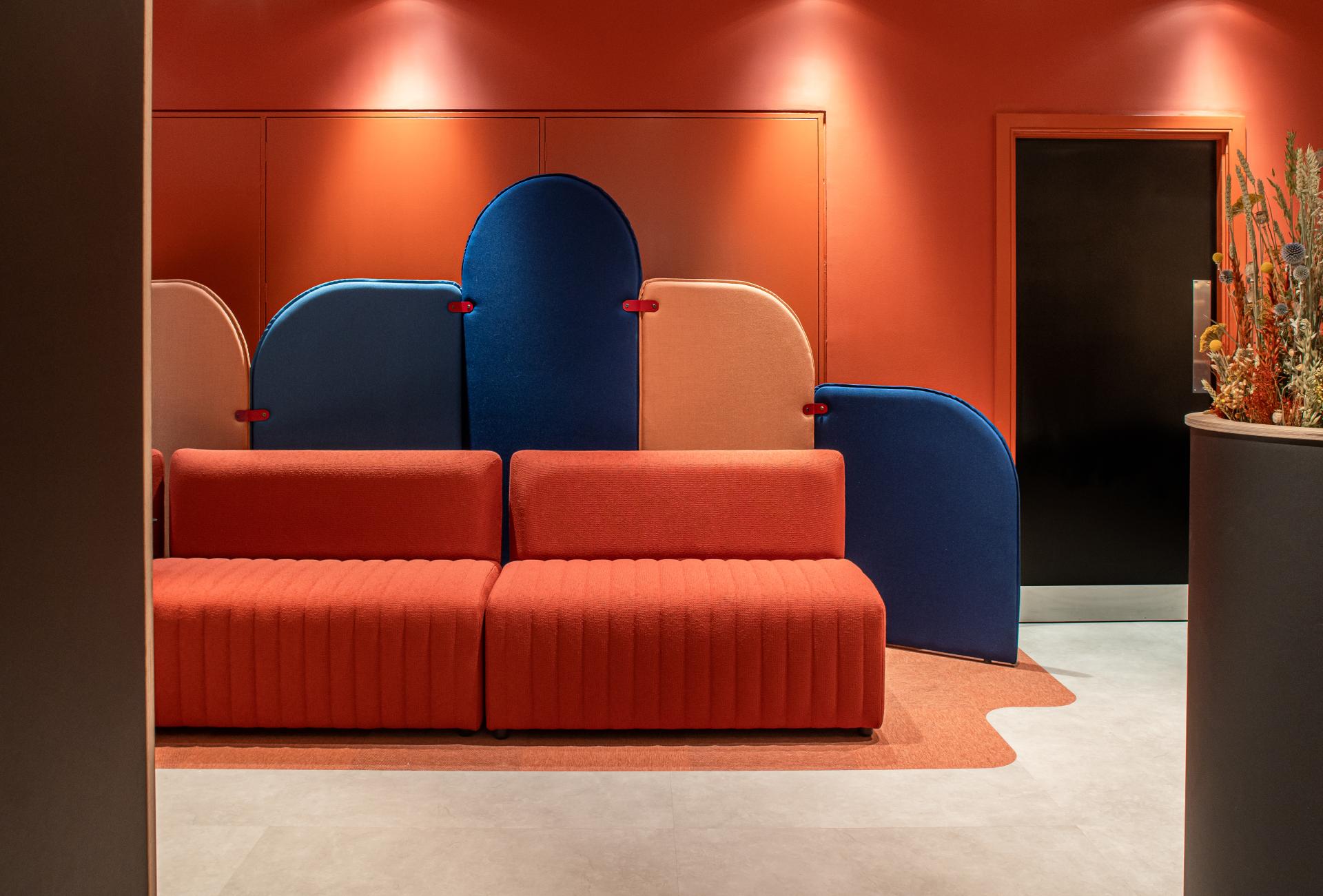 Vibrant reception area featuring a red sofa and colorful acoustic panels, showcasing innovative design for Scotland's built environment.
