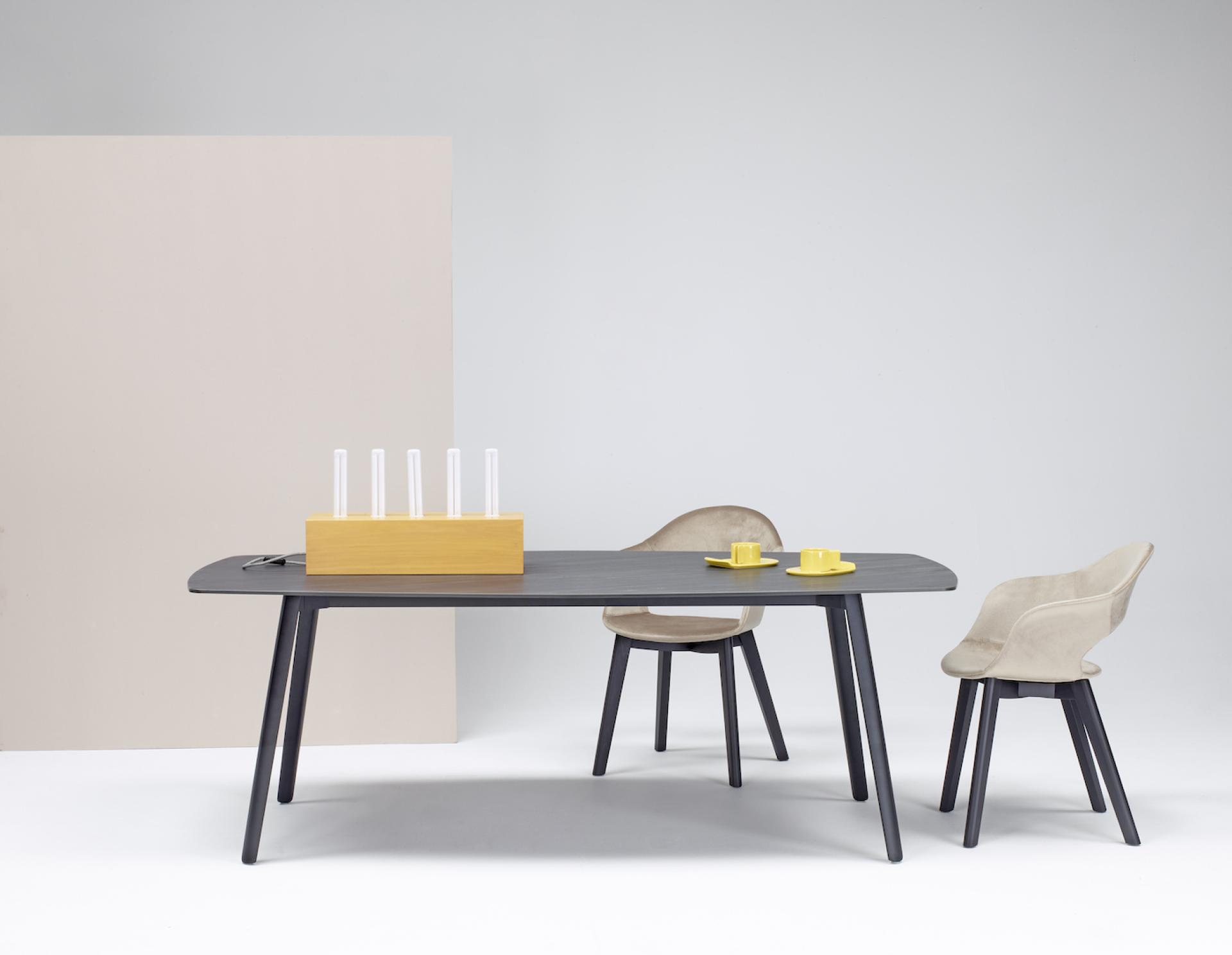 Modern table inspired by cuttlefish bone design, accompanied by sculptural chairs and minimalist decor elements.