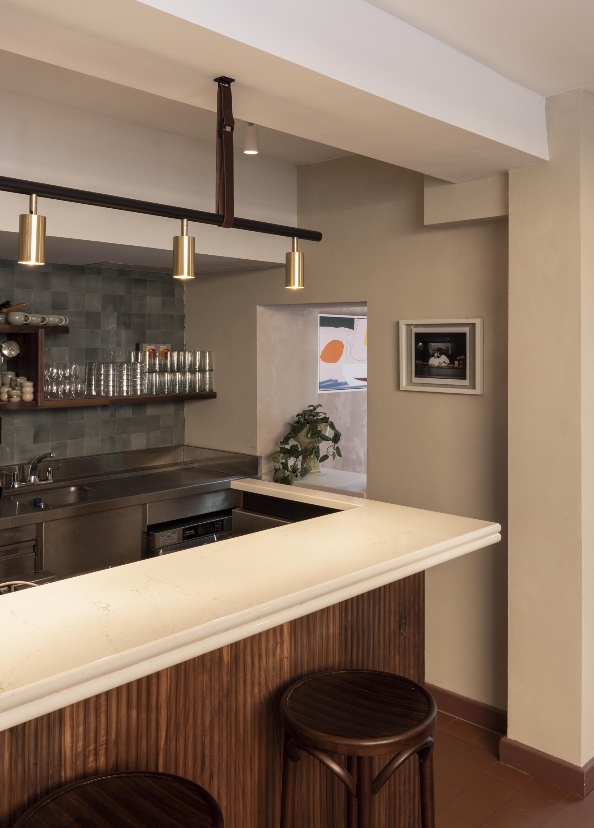 Modern bar area with elegant design elements, featuring a marble countertop, wood paneling, and glassware in Honey & Co Bloomsbury.