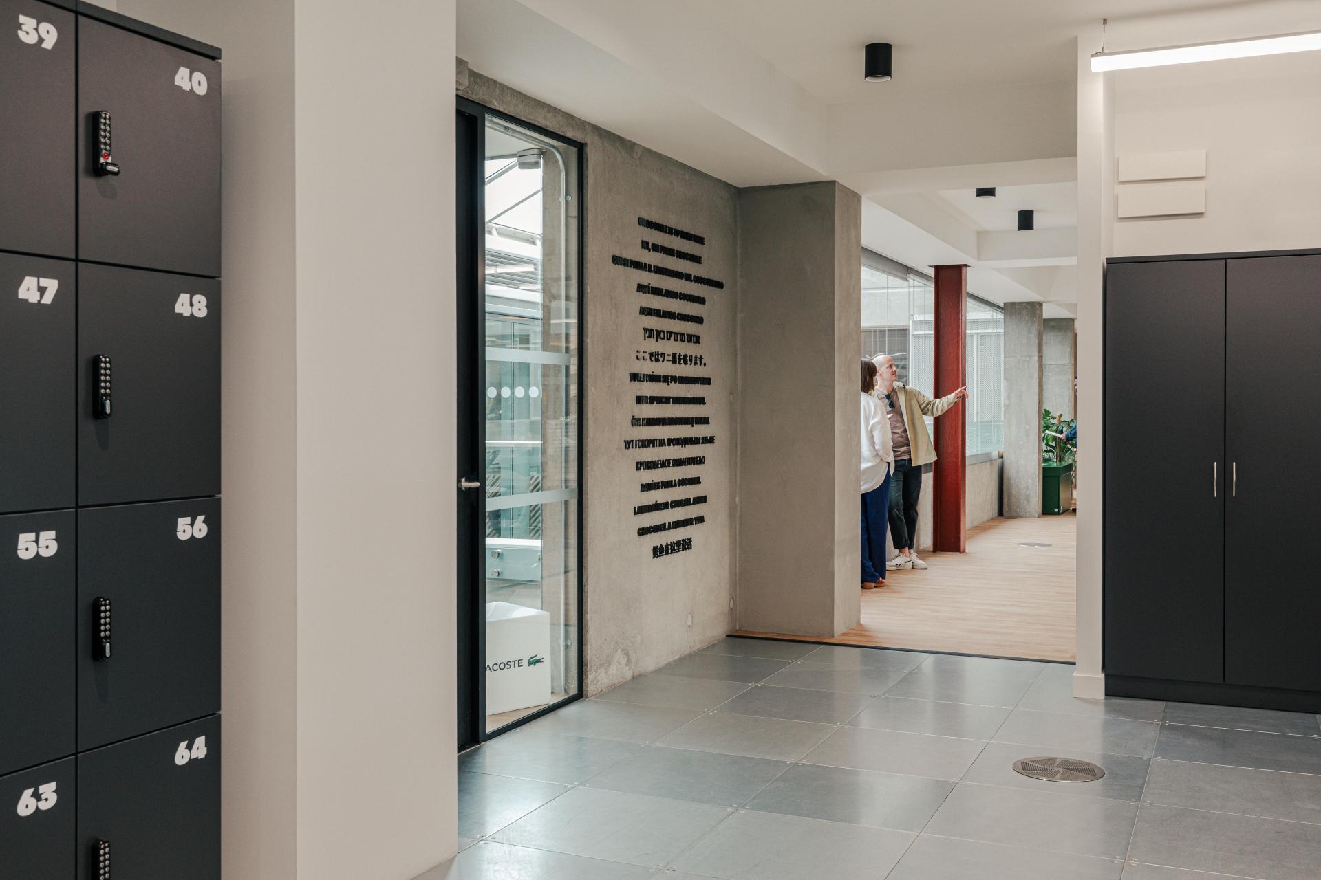 Modern Lacoste workspace featuring an industrial design with lockers and team members collaborating in an open area.