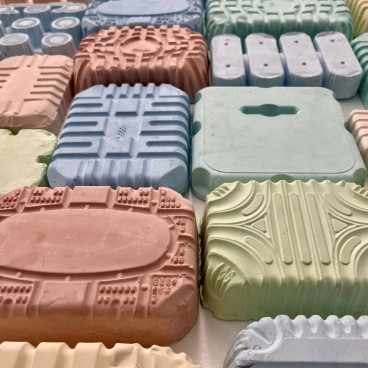 Colorful, textured plastic pieces arranged creatively, showcasing innovative approaches to reimagining plastic waste by May Wild Studio.