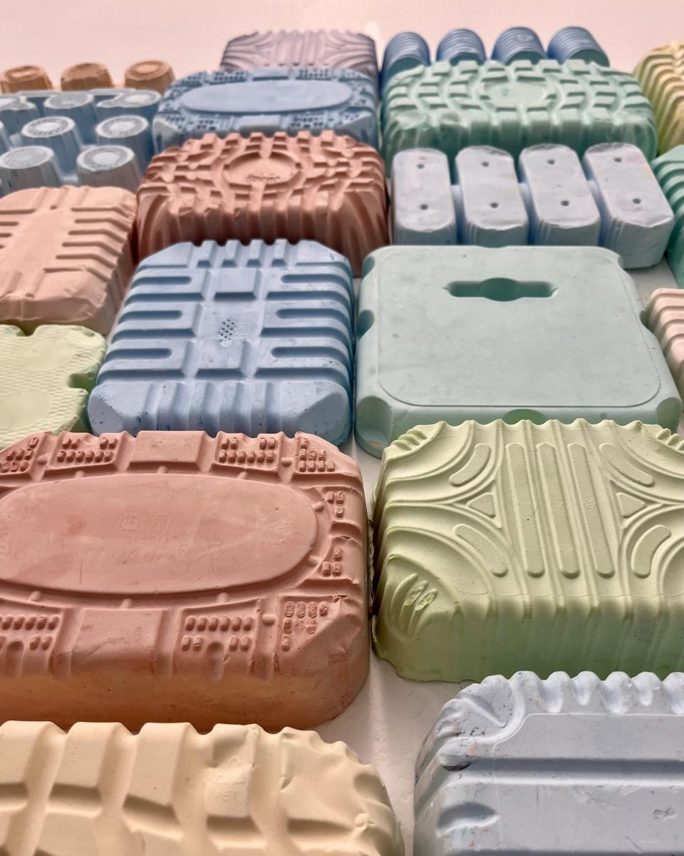 Colorful, textured plastic pieces arranged creatively, showcasing innovative approaches to reimagining plastic waste by May Wild Studio.