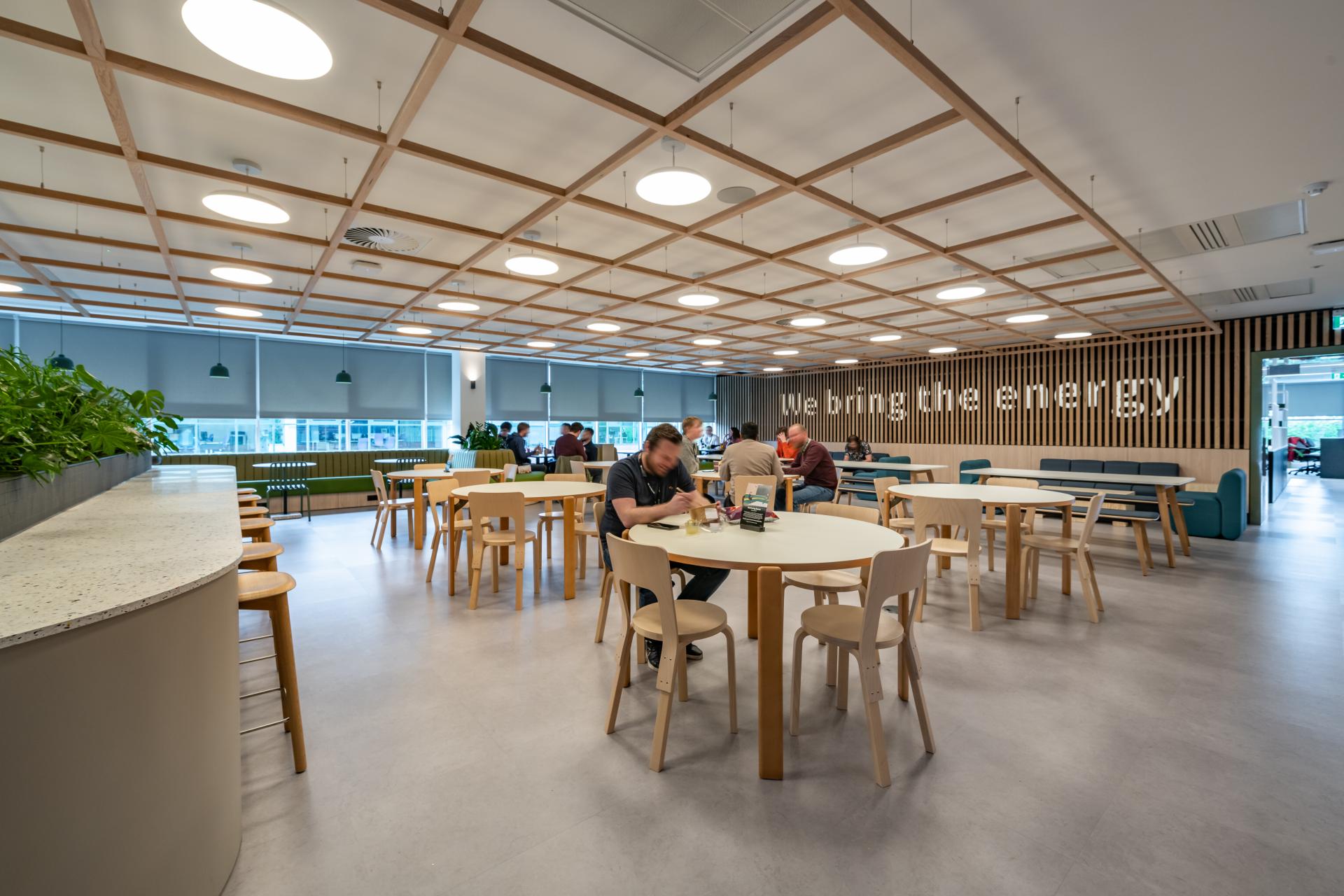 Modern office space featuring an inviting workplace design with communal tables and plants, enhancing collaboration at Conferma's FinTech headquarters.