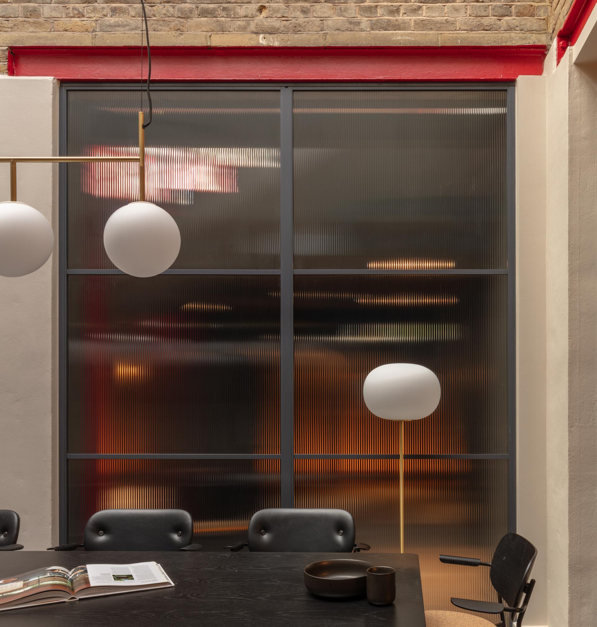 Modern co-working space with ambient lighting, featuring a stylish meeting room, contemporary furnishings, and elegant design by Holloway Li.