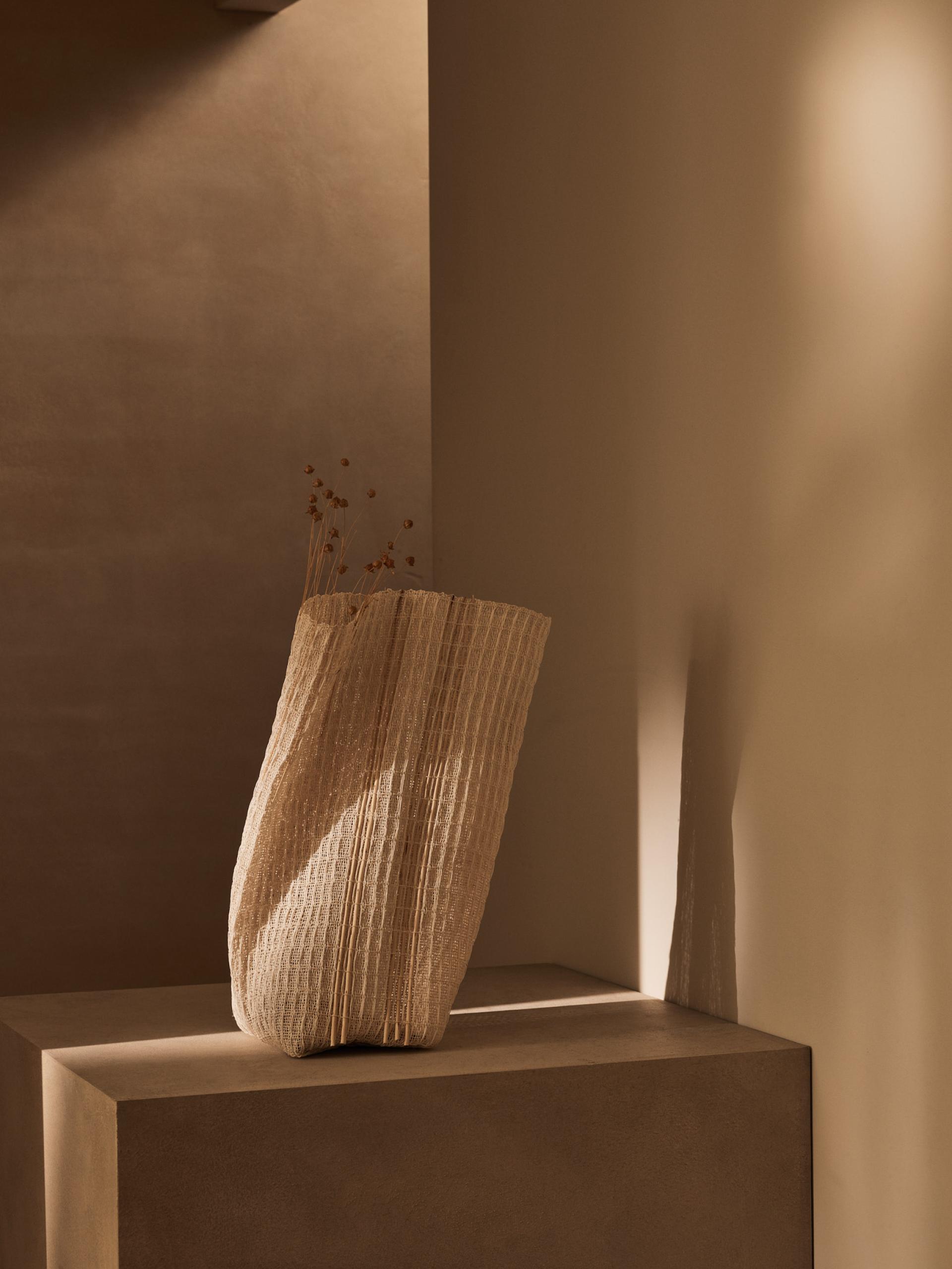 Contemporary craft vase with natural textures displayed against a warm, minimalist backdrop, highlighting modern design.