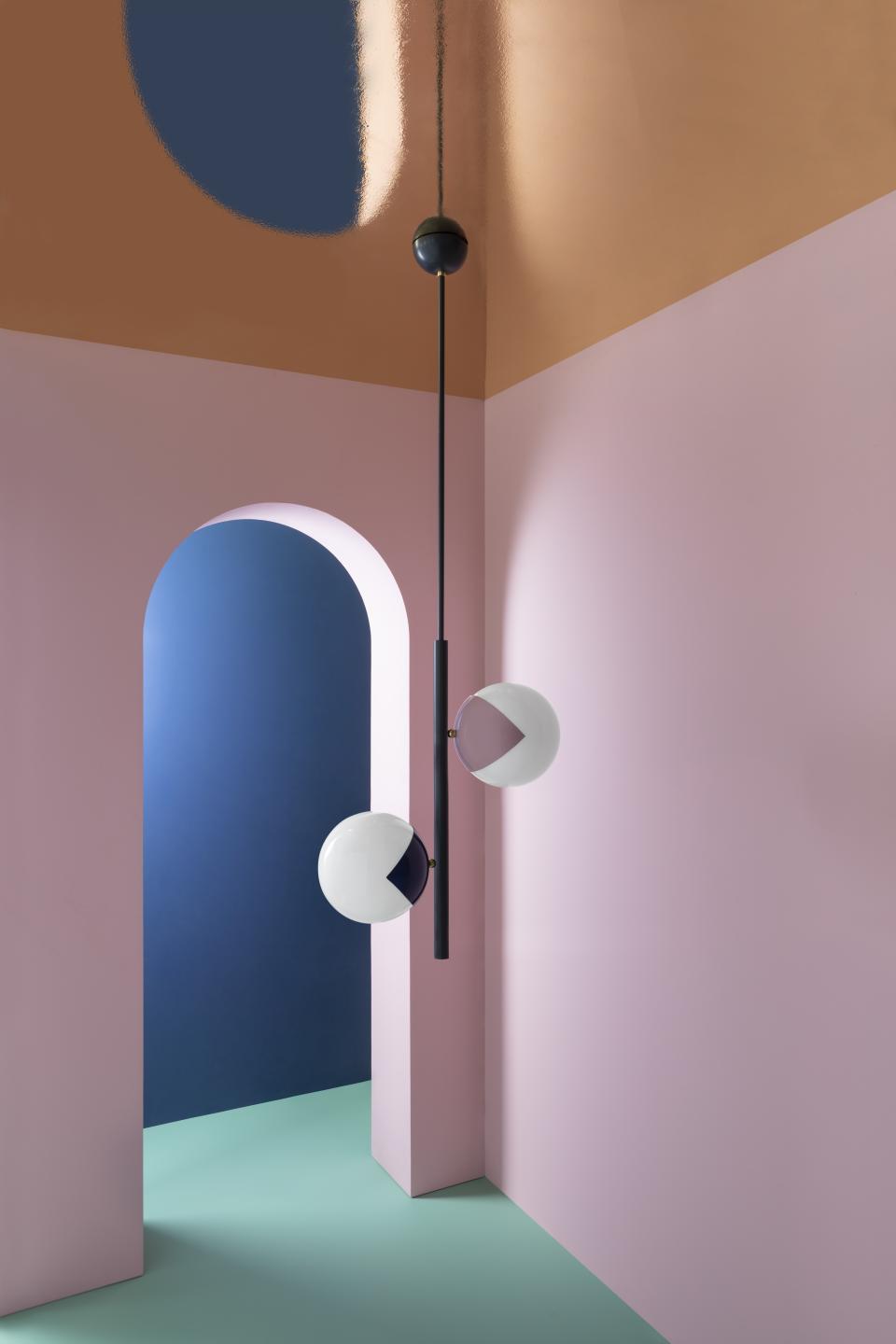 Colorful 'eyeball' lamps hanging in a modern, pastel-hued room with unique geometric architectural features.