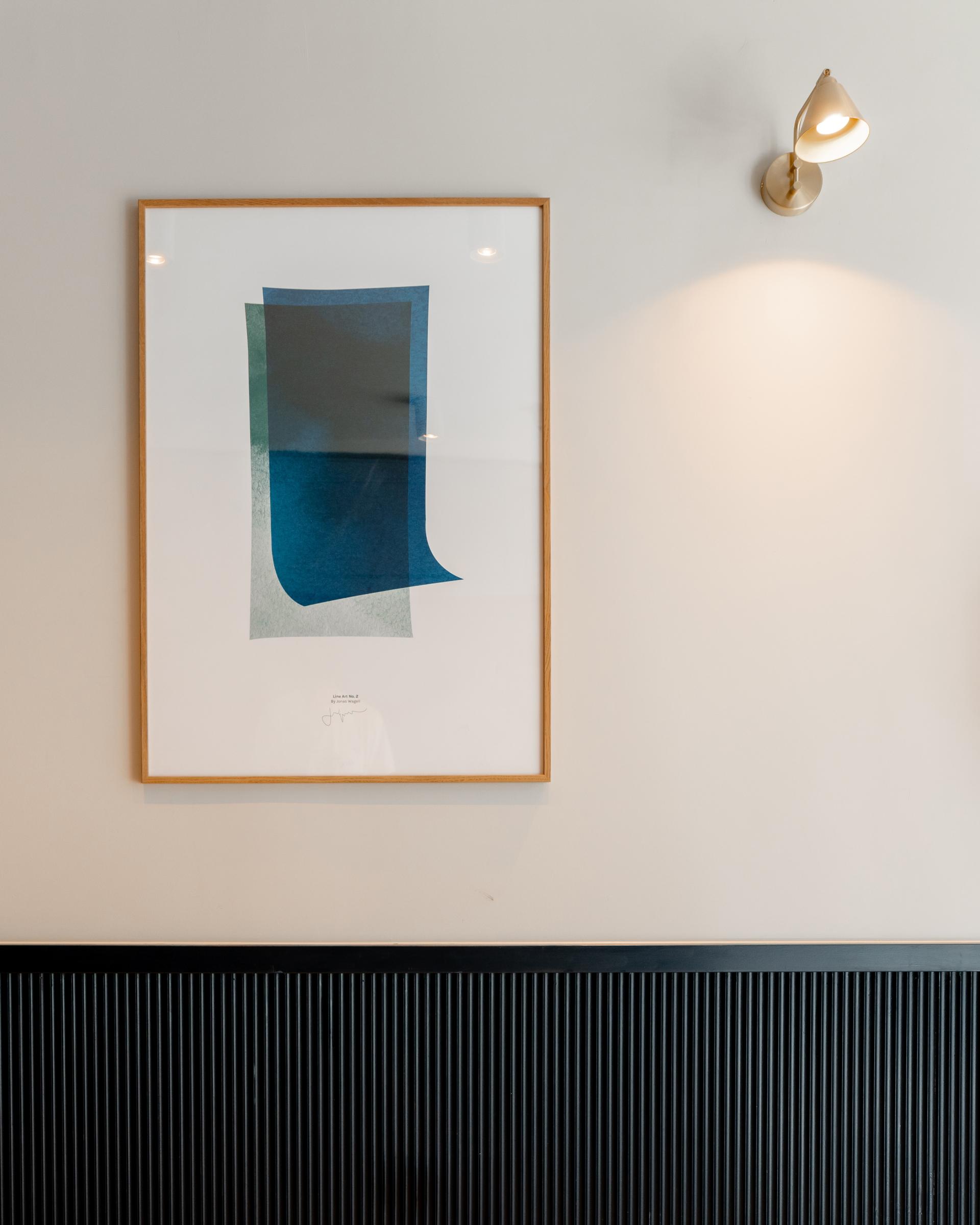 Abstract artwork featuring blue and green shapes framed on a wall in a modern co-living space at The Apiary.