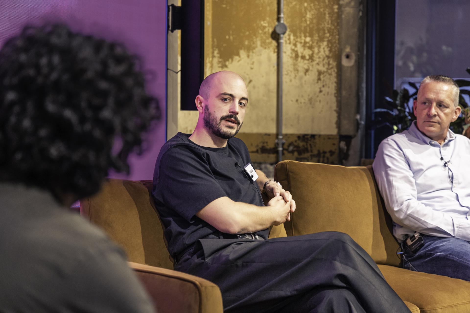 Panel discussion on technology's role in workplace adaptation post-pandemic, featuring three engaged speakers on a sofa.