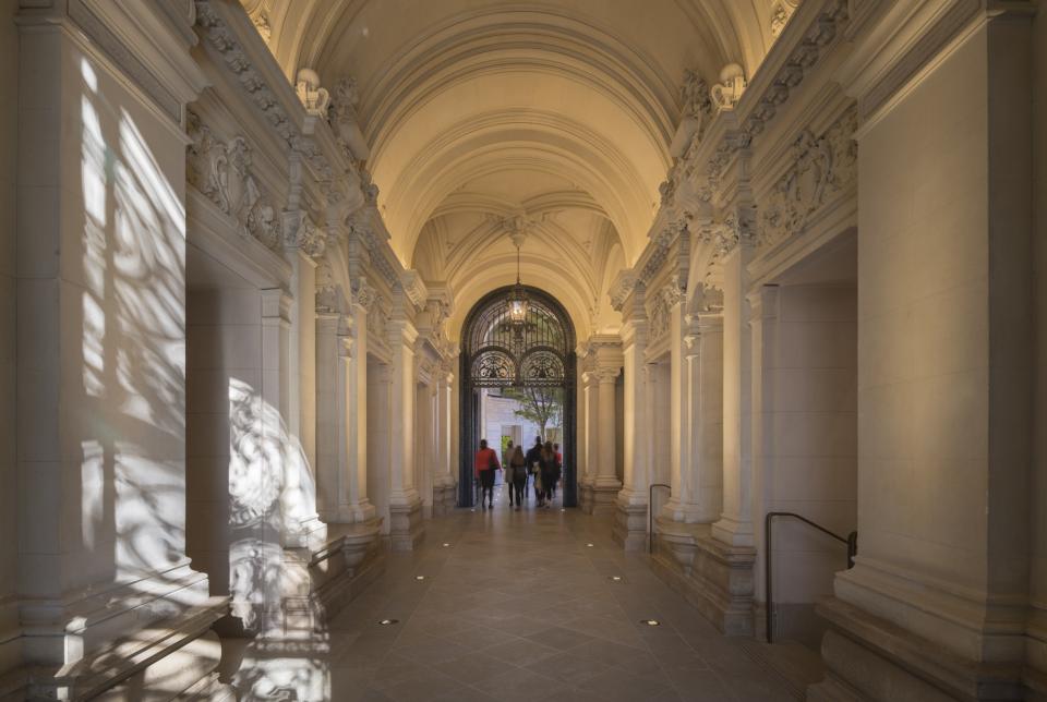 Elegant corridor showcasing intricate architectural details leading to the entrance of Apple's Champs-Élysées store in Paris.