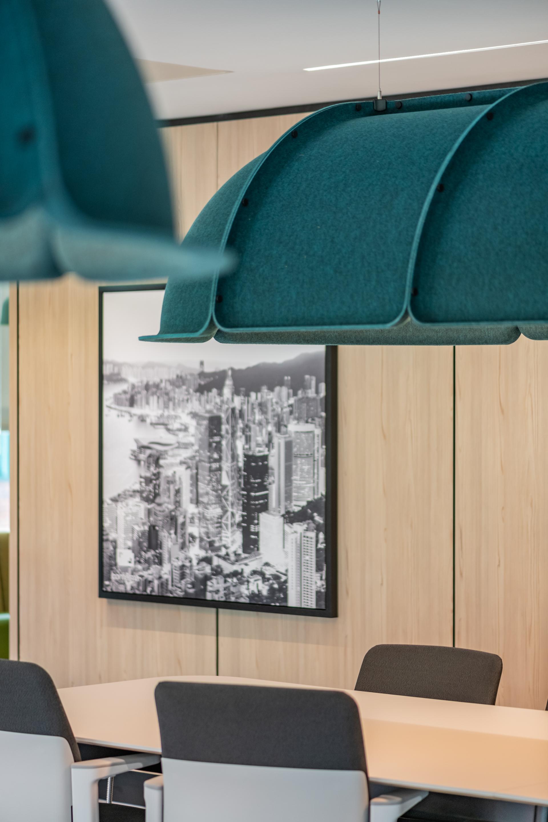 Modern office meeting space featuring teal acoustic lighting and a large black-and-white cityscape photo.