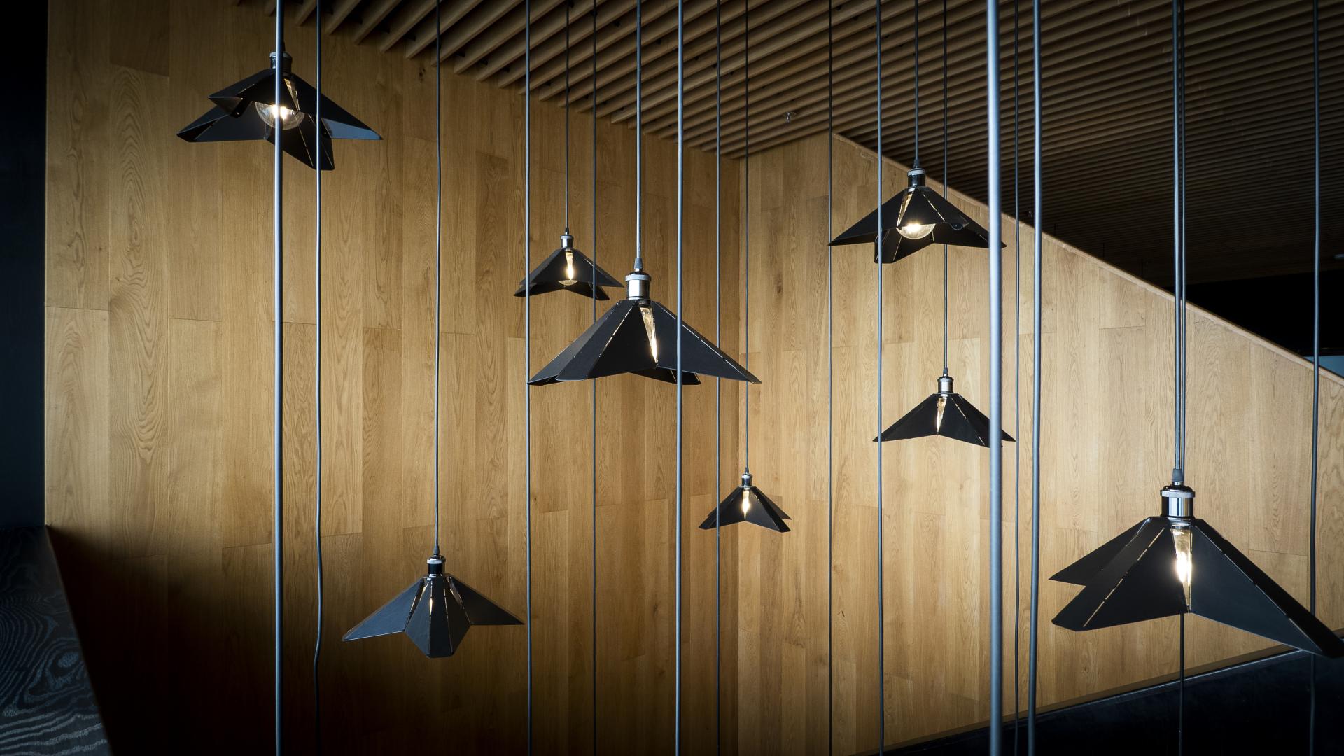 Modern pendant lights hang from cables against a wooden wall, enhancing the stylish atmosphere of Brew92 coffee shop.
