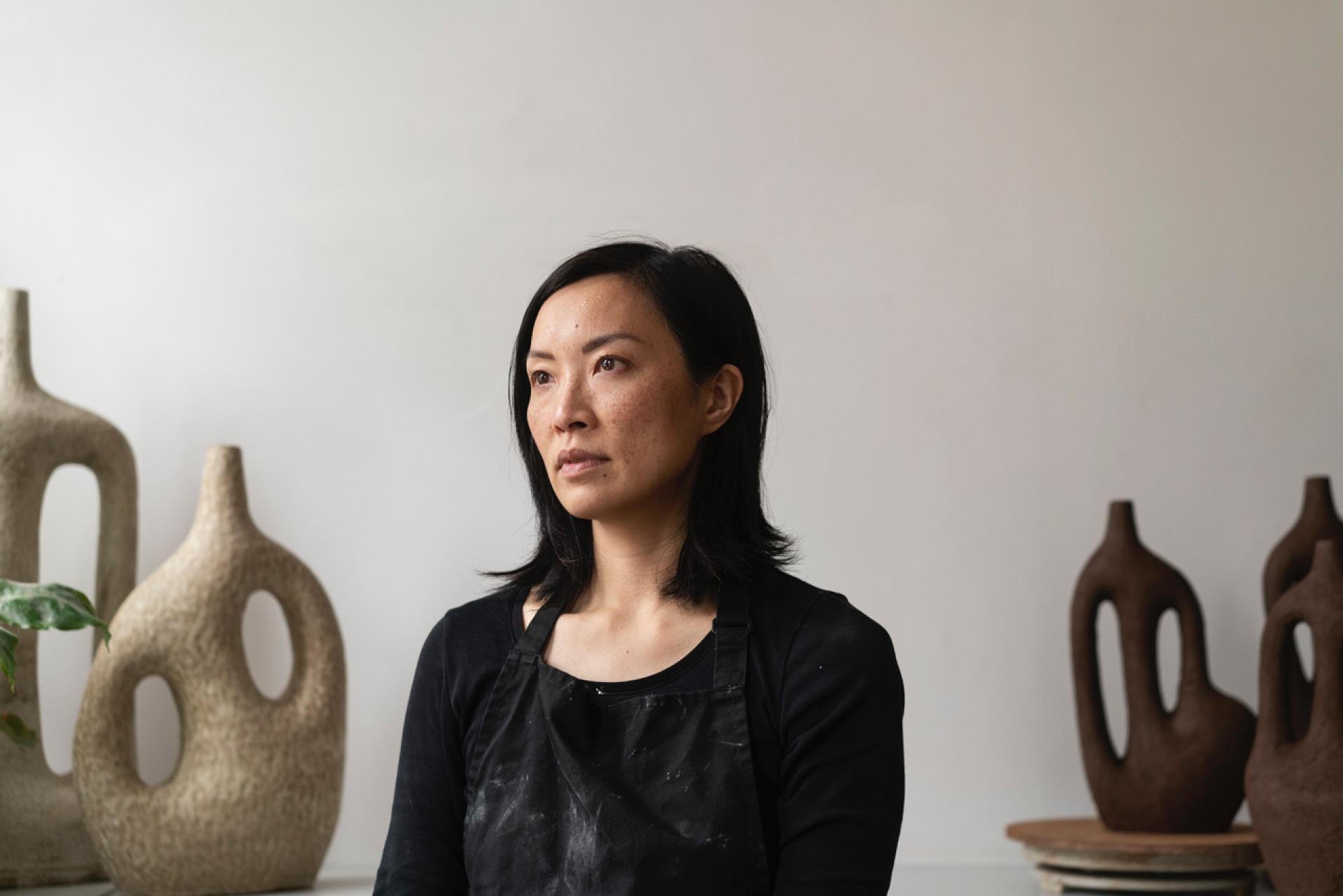 Portrait of a female potter in a studio, surrounded by unique ceramic sculptures, celebrating Glasgow's creative craft scene.
