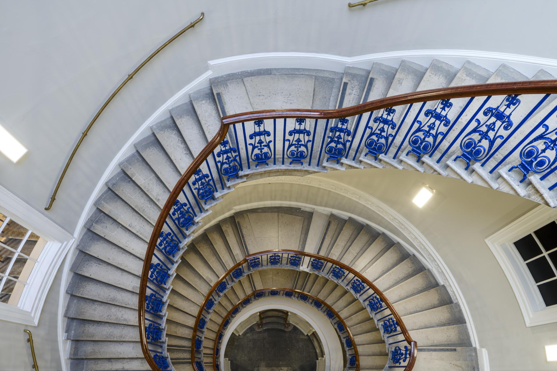 Curved staircase with ornate blue railing at The Courtauld Gallery, showcasing the redesigned visitor experience.