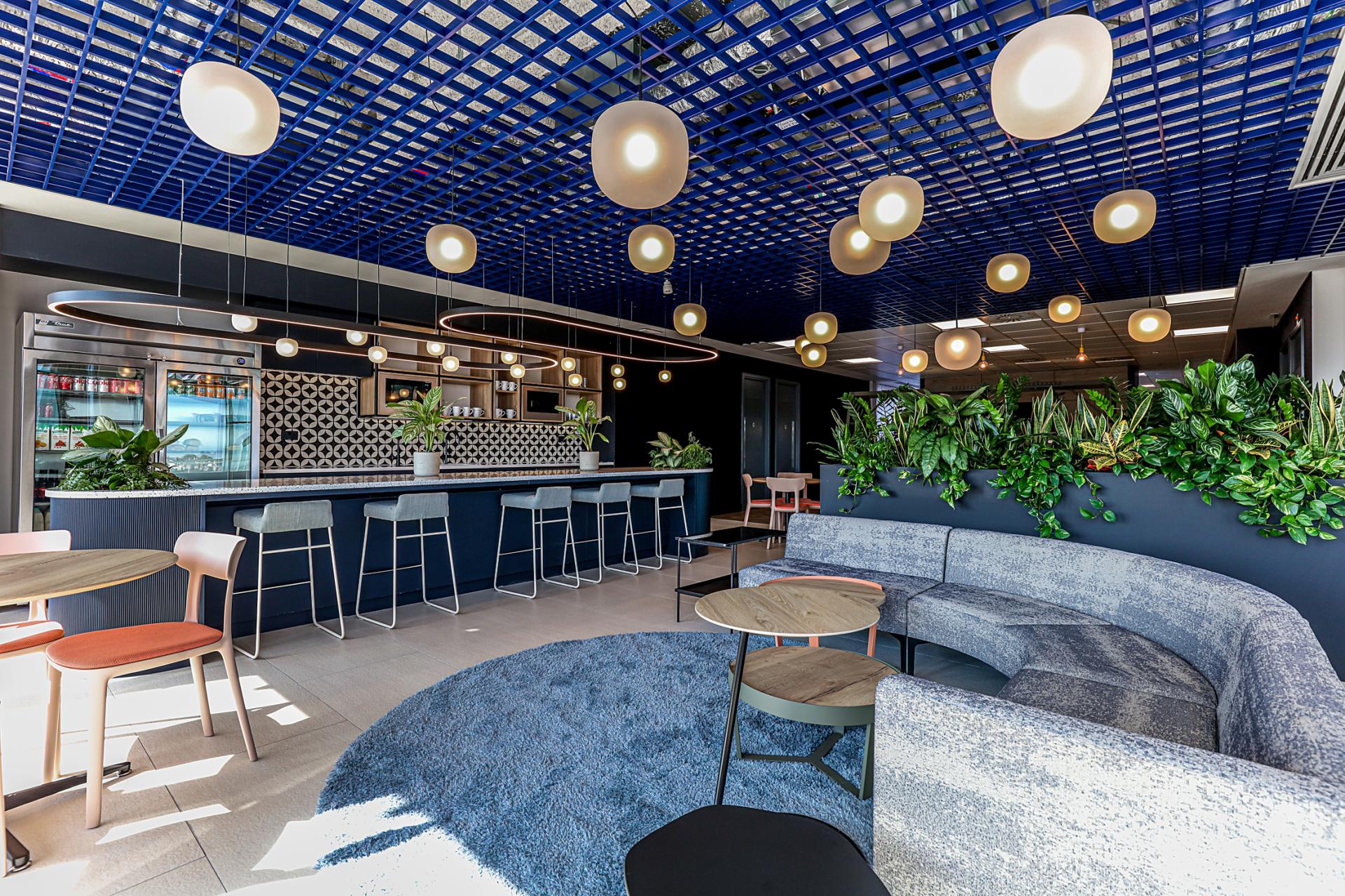 Modern office lounge at Domestic & General’s Wimbledon HQ featuring stylish seating, vibrant decor, and greenery.