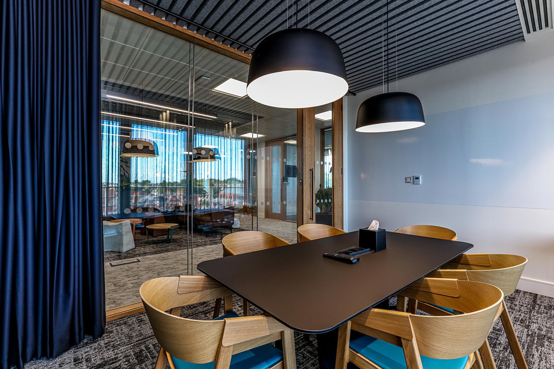 Modern conference room featuring sleek furniture, hanging lights, and large windows showcasing the Wimbledon area, emphasizing Domestic & General's office upgrade.