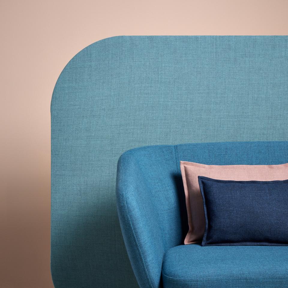 Soft blue Sumi fabric upholstery on a modern chair with decorative pillows in pink and navy colors.