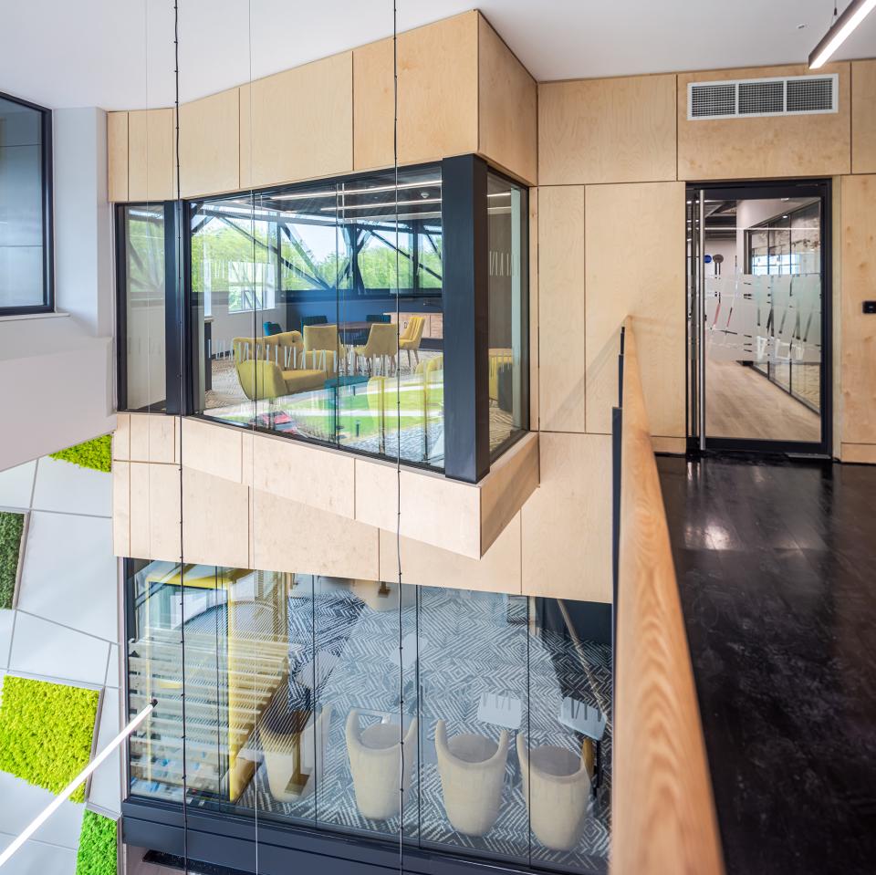 Modern flexible workspace interior at The Bee House, featuring glass meeting rooms and stylish seating arrangements.