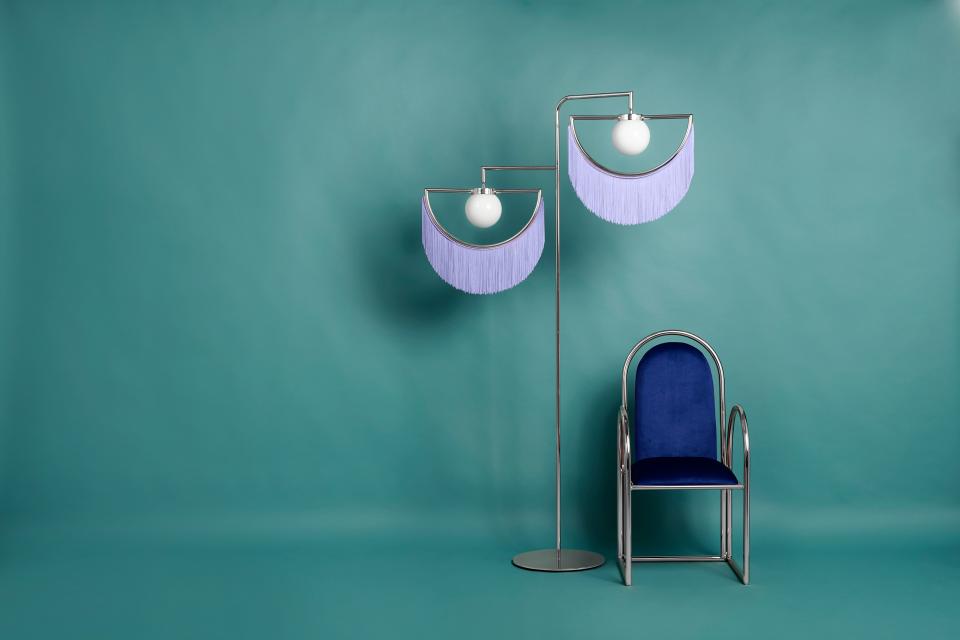 Stylish vintage-inspired floor lamp and chair on a teal background, showcasing Masquespacio and Houtique's new collection.