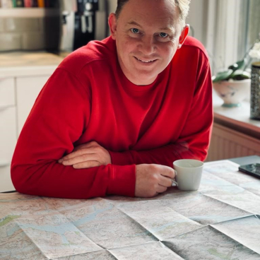 Rodi McLean, founder of Form Design Consultants, relaxes with a map and coffee in a sustainable workspace.