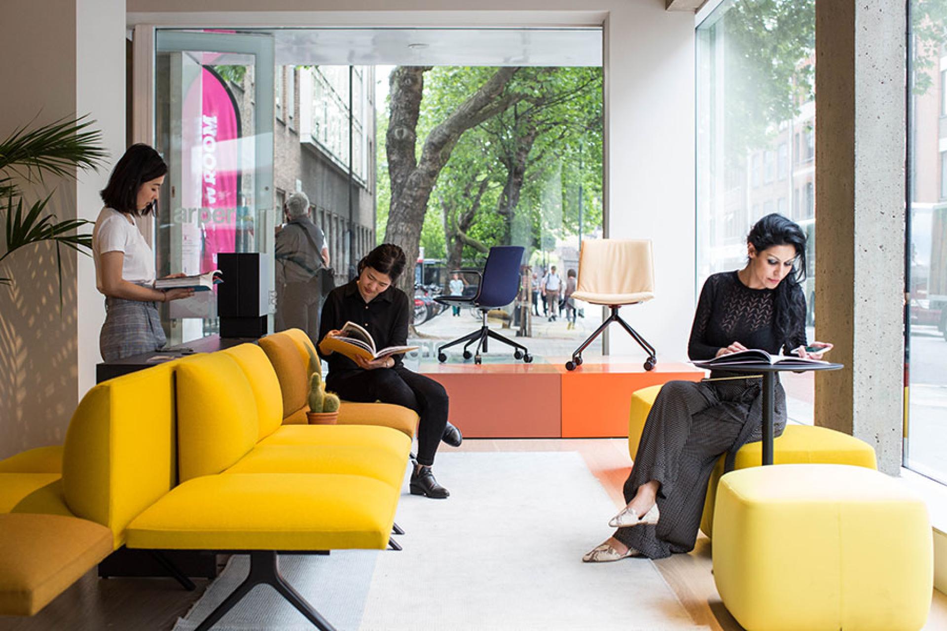 Creative workspace at Clerkenwell Design Week, showcasing attendees reading and stylish furniture in a vibrant setting.