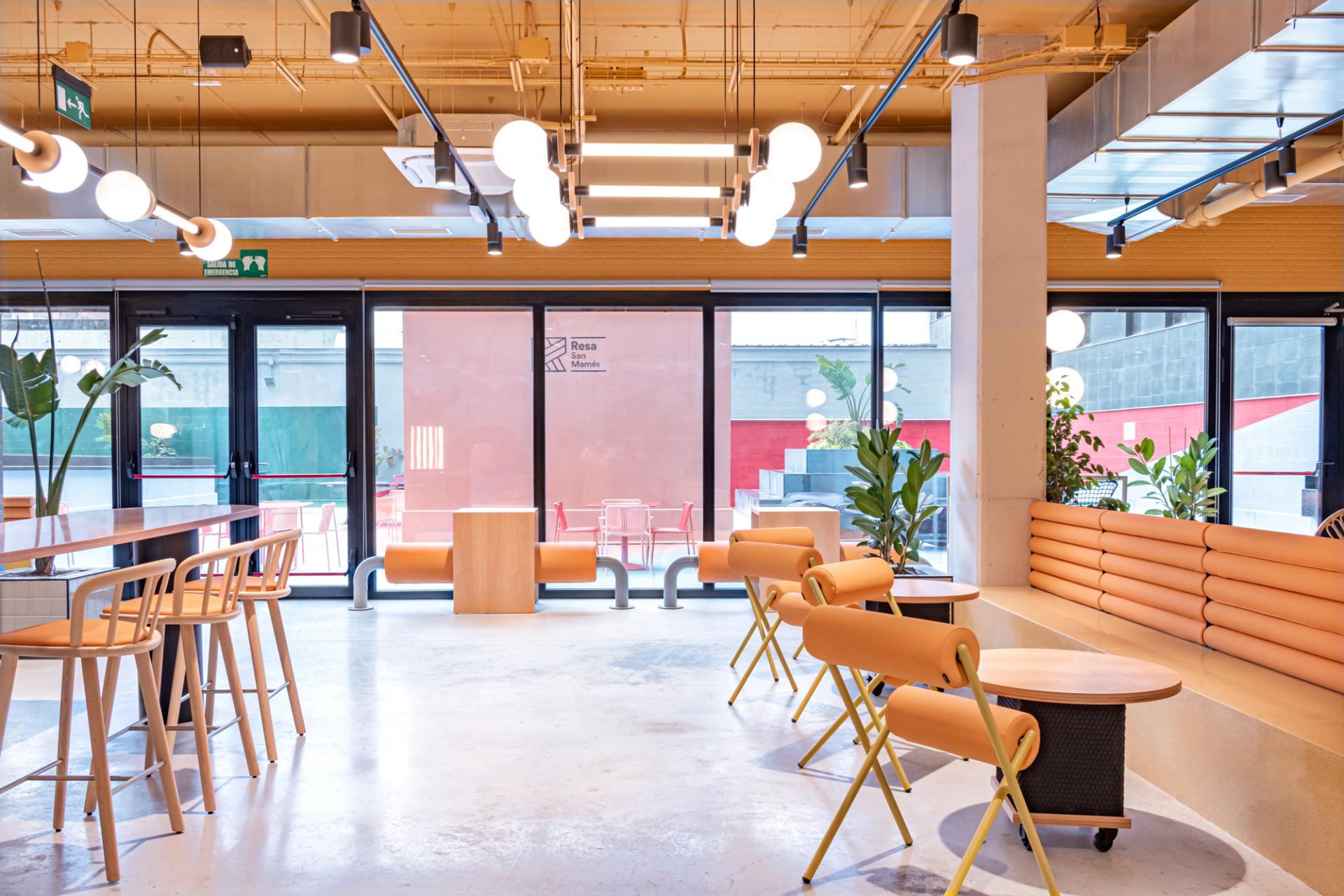 Contemporary student residence lounge featuring vibrant Wes Anderson-inspired design, plant accents, and stylish furniture in Bilbao.