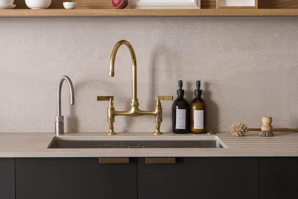 Stylish kitchen sink setup featuring gold and silver faucets, decorative storage bottles, and a minimalist design.