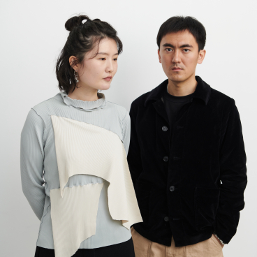 Zhekai Zhang and a collaborator pose in contemporary fashion showcasing innovative textiles, emphasizing sustainable design practices.