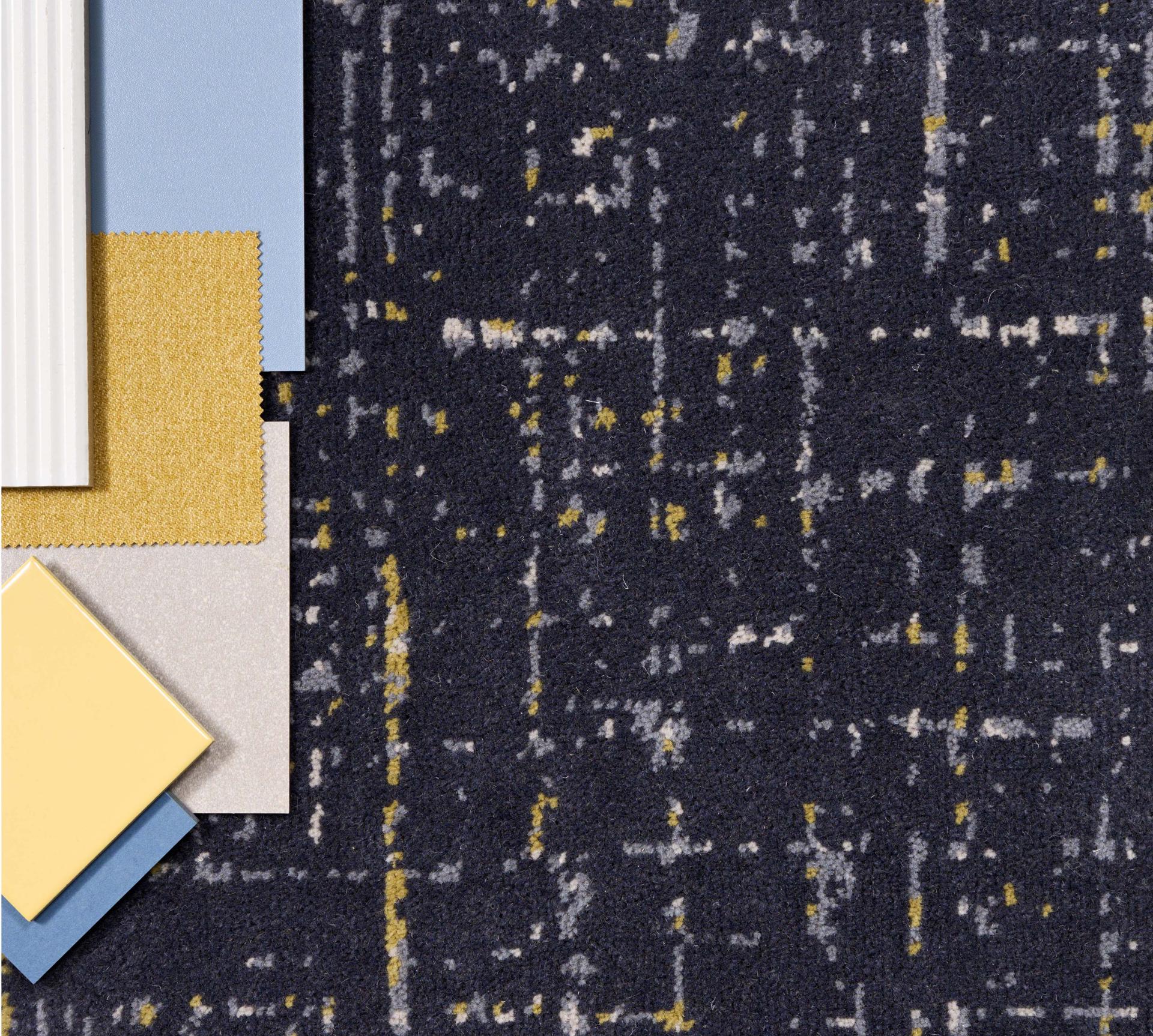 Textured carpet sample in dark hues with vibrant accents, paired with fabric swatches, representing Newhey's latest collection inspired by Lancashire landscapes.