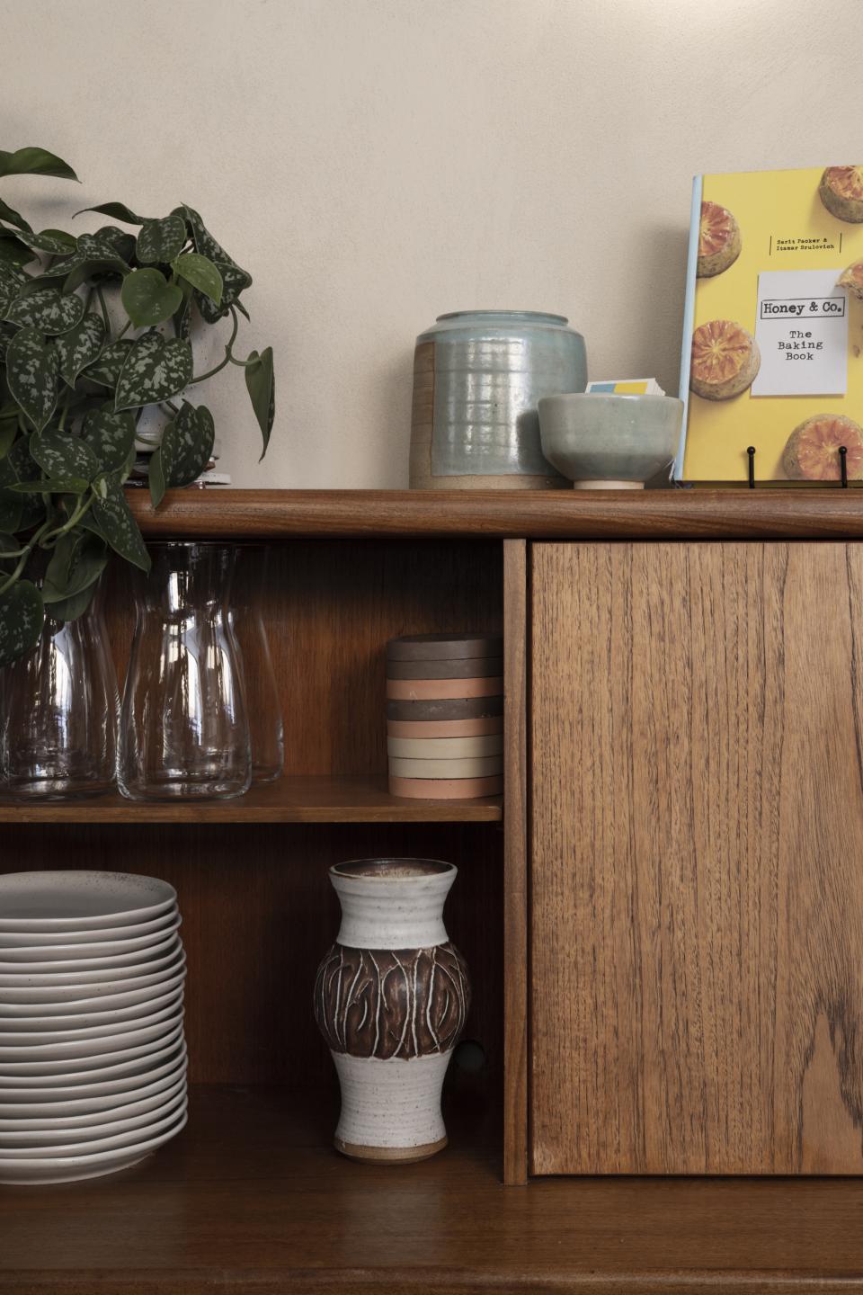 Stylish wooden shelf featuring decorative ceramics, glassware, and a cookery book from Honey & Co, enhancing the restaurant's design.