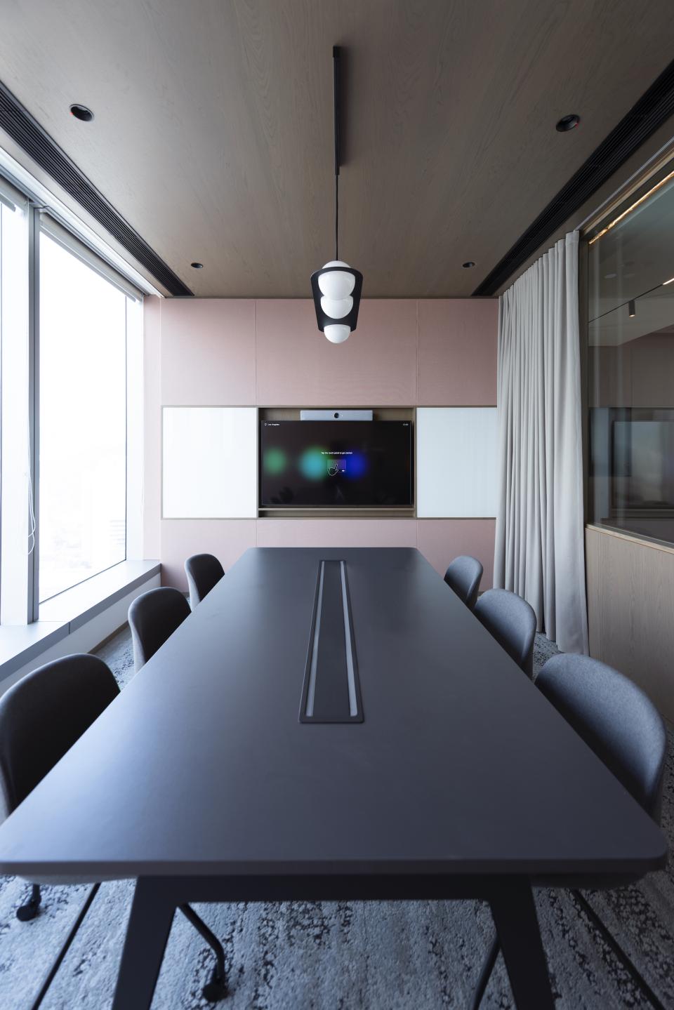 Modern conference room designed by Bean Buro for Warner Music Hong Kong, featuring a sleek table and technology integration.