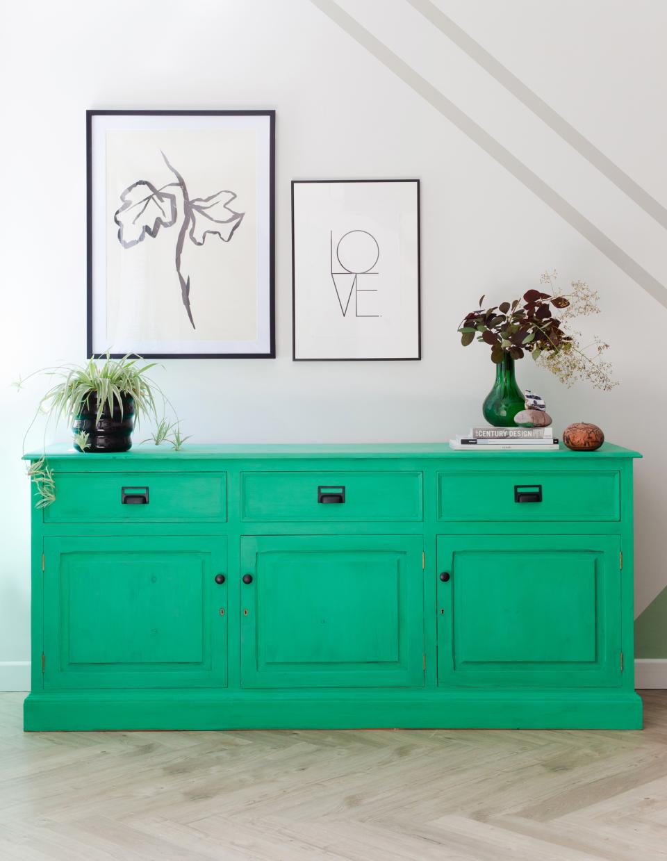 Vibrant green sideboard against a light wall, accompanied by contemporary artwork and decorative plants, showcasing Scandi Industrial design.