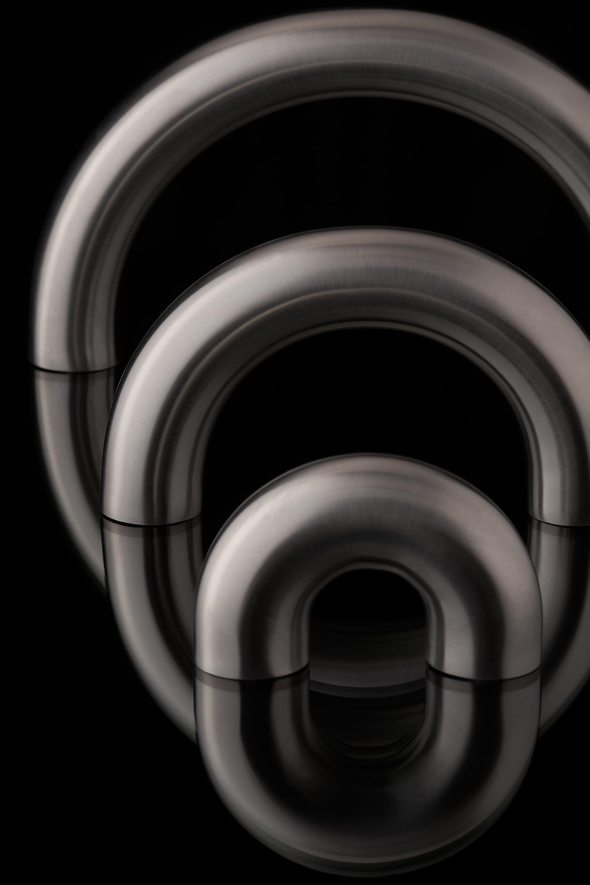 Elegant architectural ironmongery pieces designed by Tom Dixon, featuring sleek metal finishes and modern shapes.