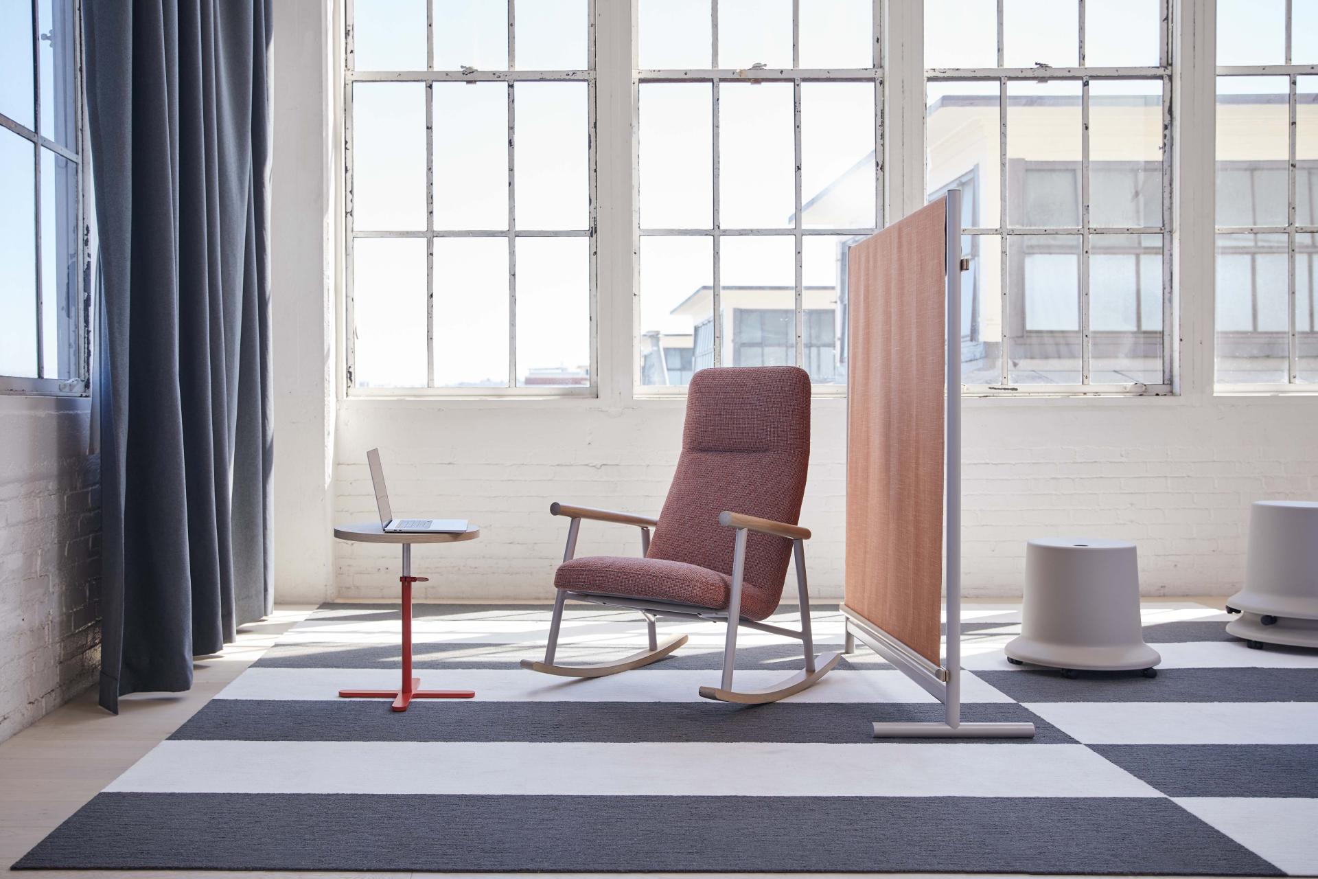 Stylish rocking chair and table set in bright workspace, showcasing Pearson Lloyd’s Routes furniture collection for modern offices.