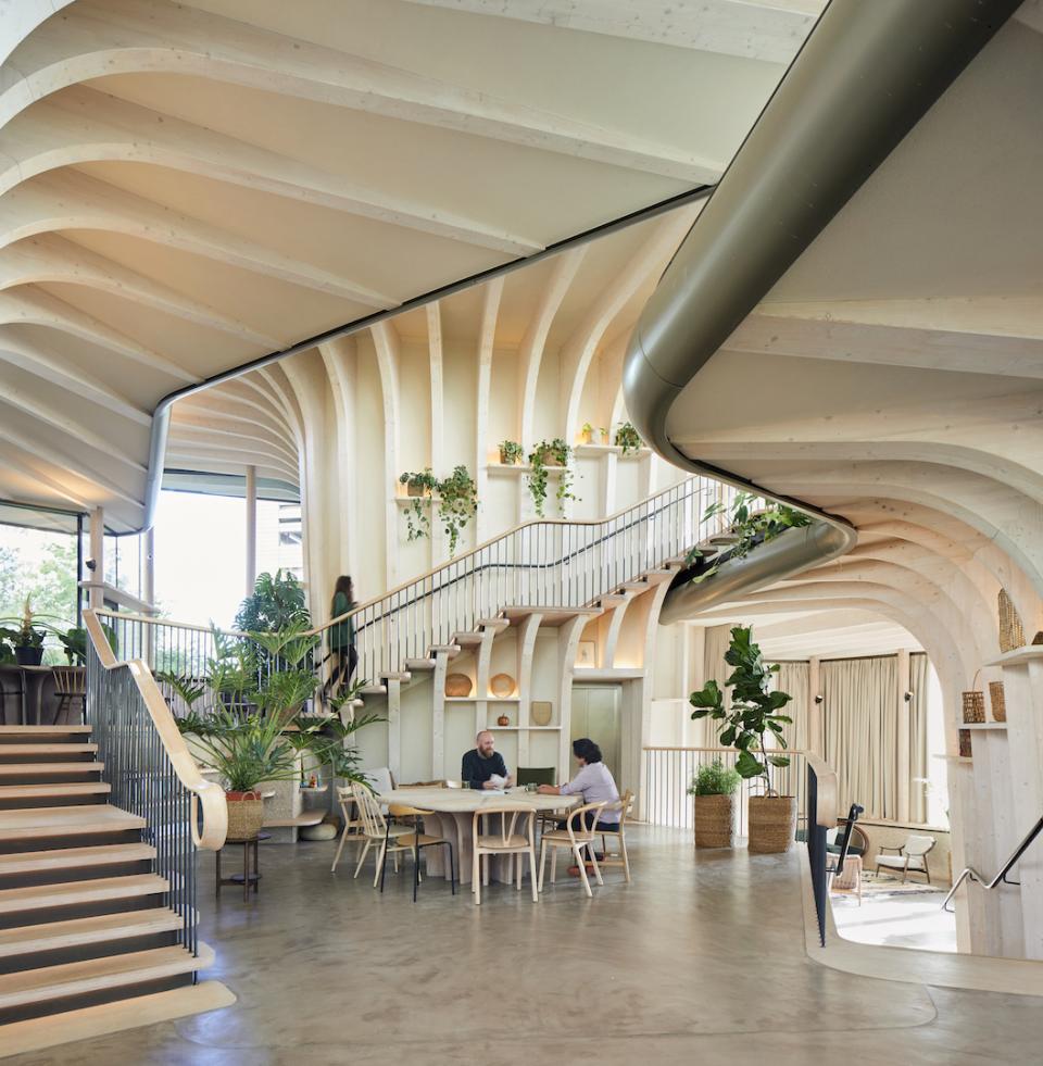 Interior view of Maggie's Leeds, showcasing organic architecture with wooden curves, greenery, and community spaces for emotional support.