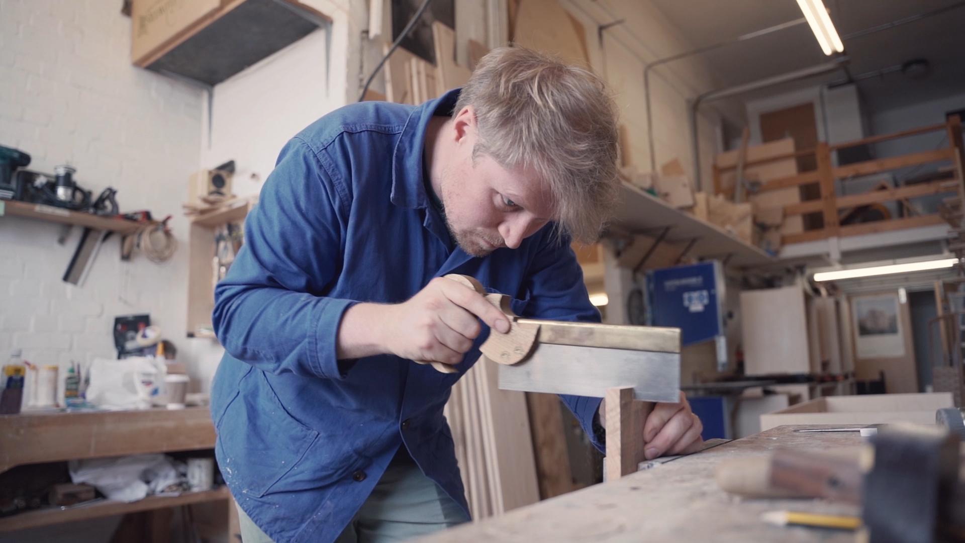 Craftsman measuring wood with a ruler in a workshop, highlighting traditional craftsmanship for Harewood Biennial 2022.