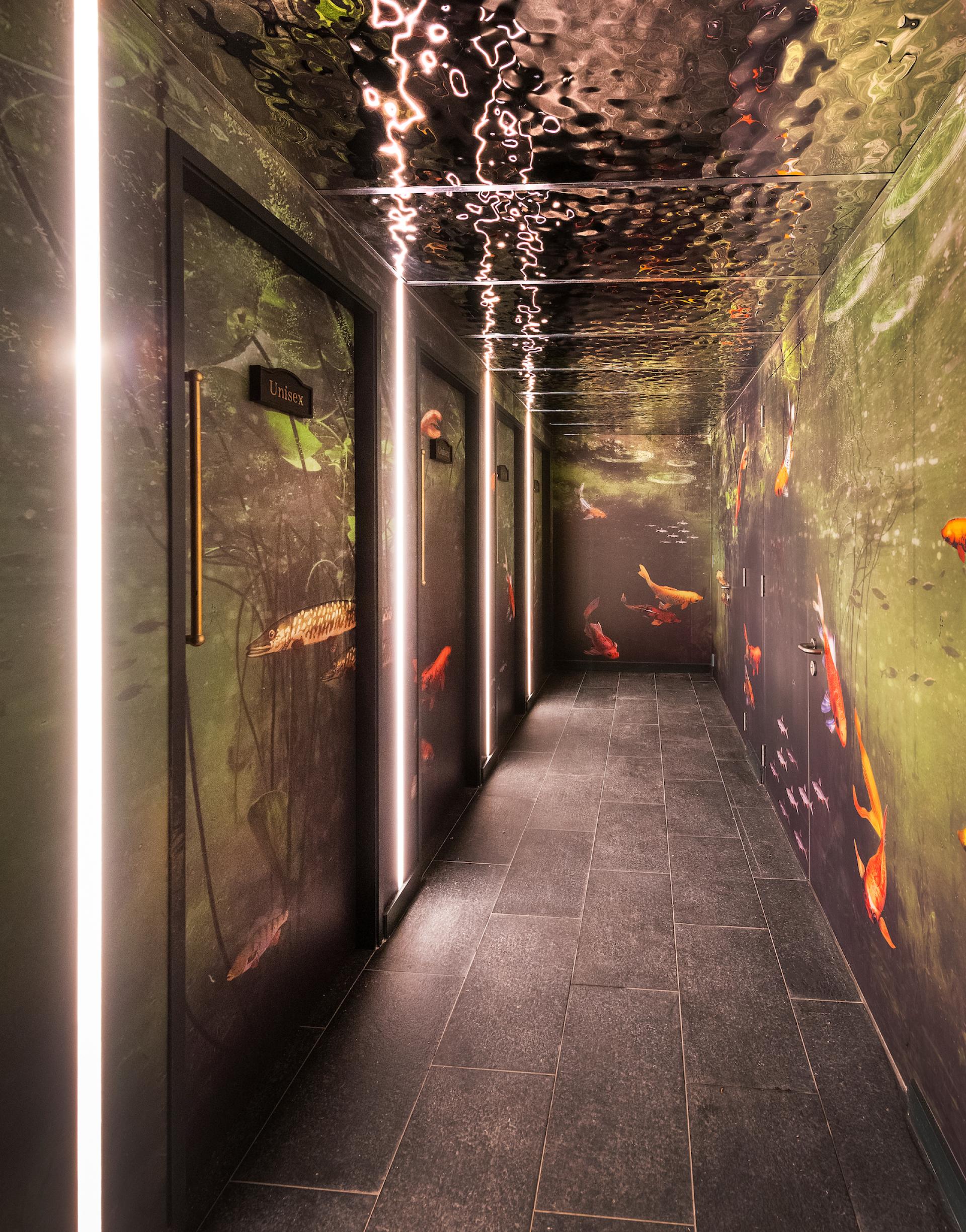 A creatively designed hallway featuring aquatic-themed murals and soft, illuminated accents, enhancing the Wonderland experience.