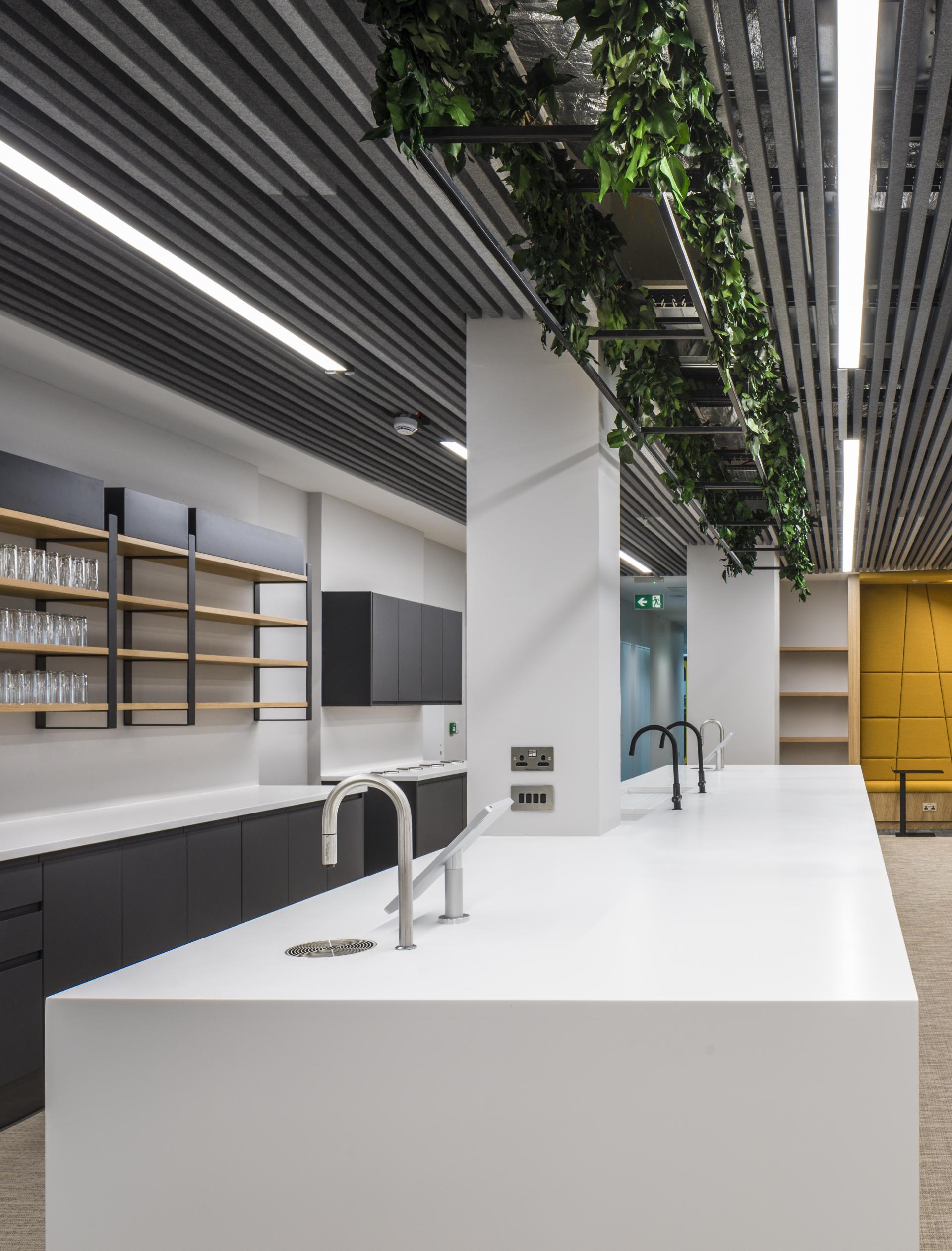 Modern office kitchen featuring sleek white countertop, dark cabinetry, and greenery, part of Scotland's first WELL certified space.