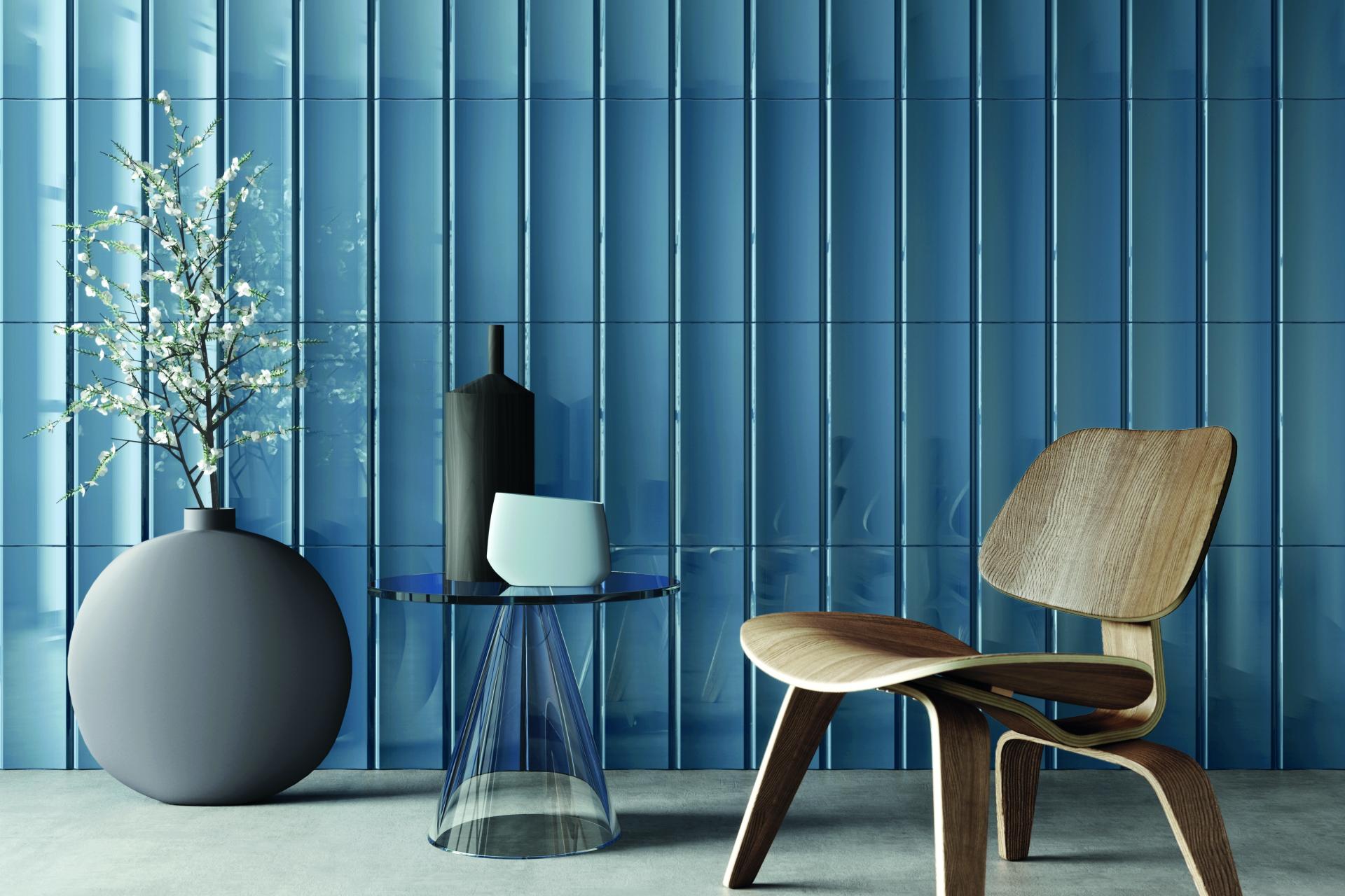 Stylish interior featuring a blue tiled wall, modern wooden chair, decorative vases, and a glass table, showcasing Tile of Spain’s design trends.