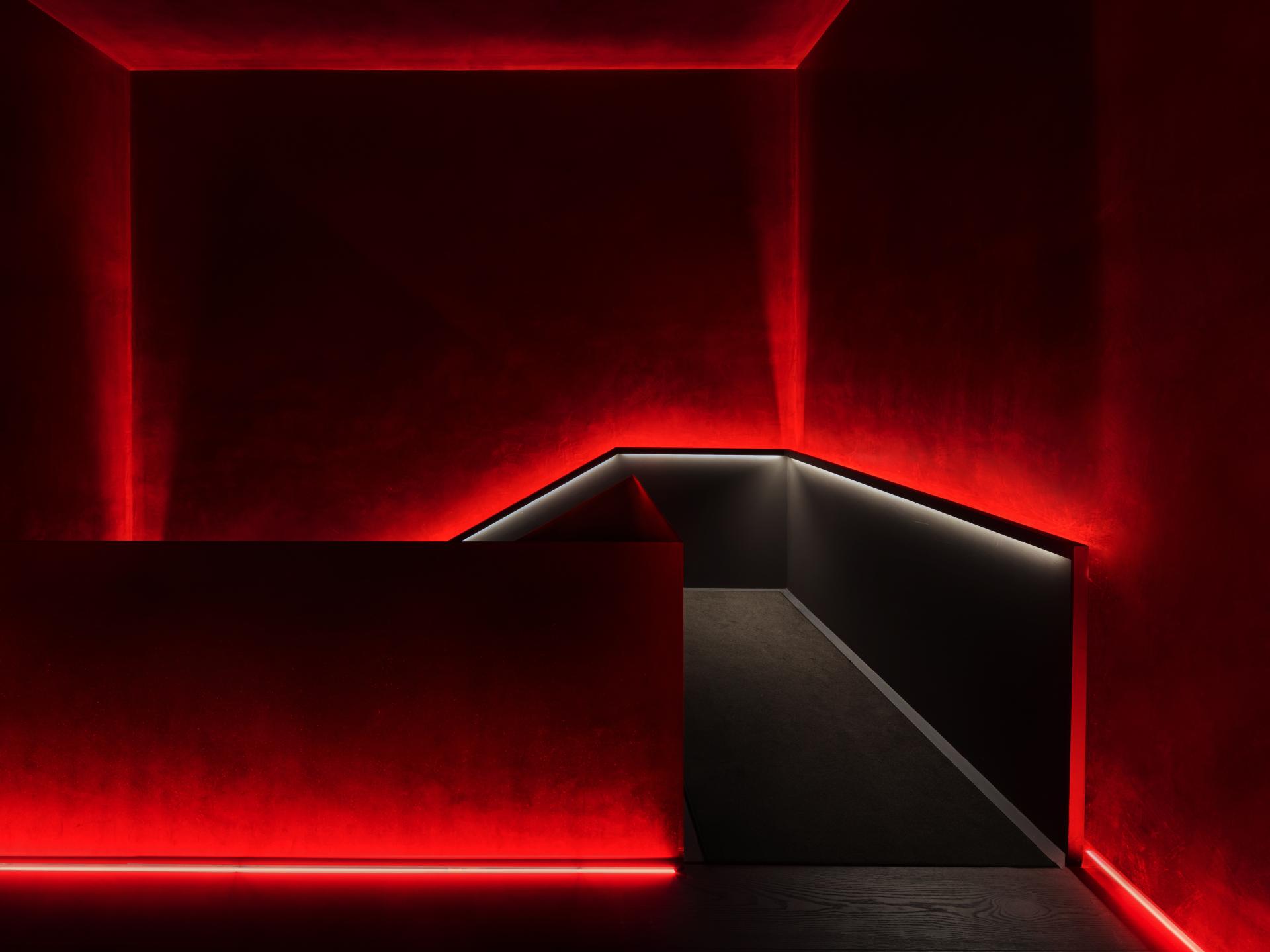 Luxurious red-lit corridor in Barcelona EDITION, showcasing modern design and exclusive ambiance of premium suites.