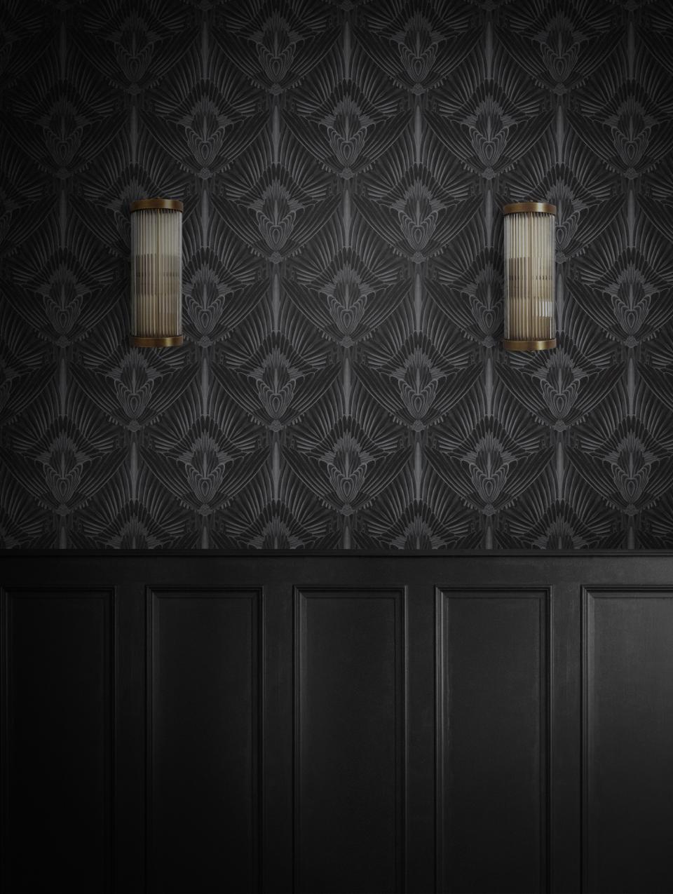 Glamorous black wallpaper with intricate patterns, accented by stylish wall sconces, showcasing Divine Savages' unique design aesthetic.