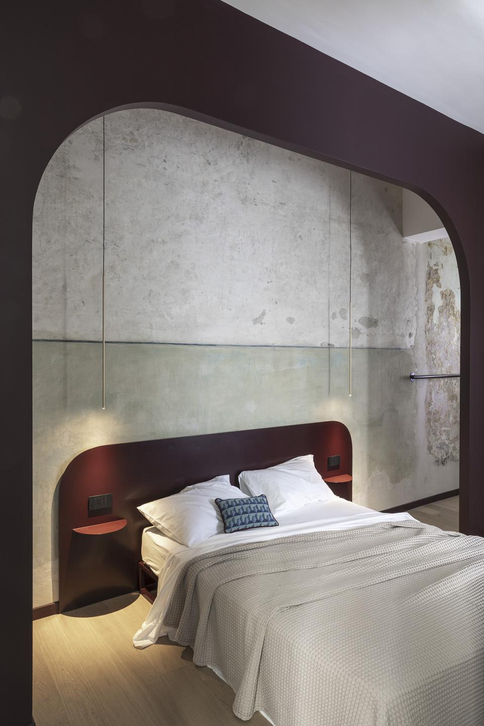 Modern bedroom interior in a Trastevere apartment, featuring a minimalist design, textured walls, and rich color accents.