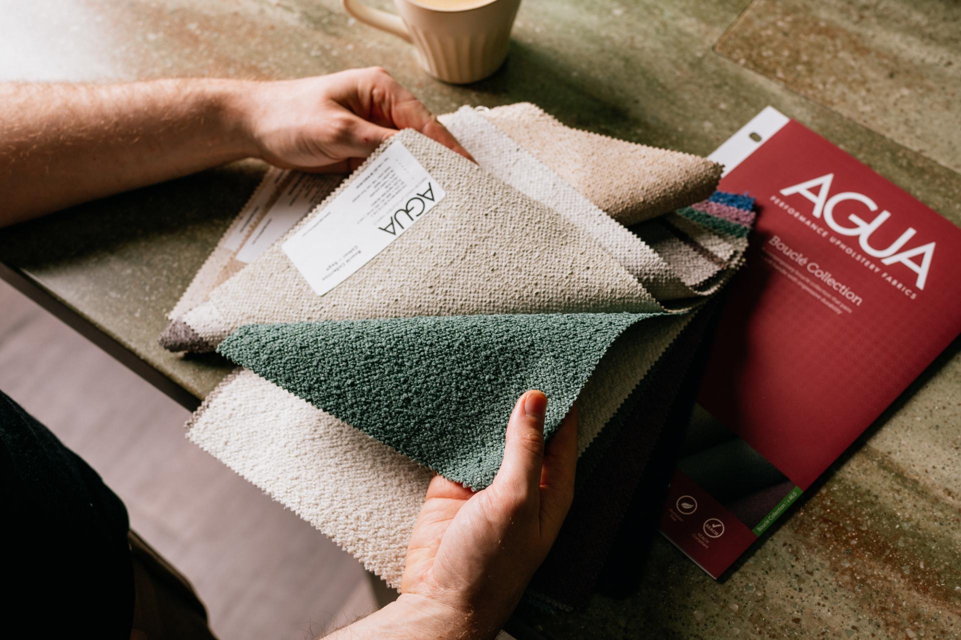 Textured upholstery samples in various colors displayed on a surface, showcasing Agua Fabrics' Eden and Bouclé collections.