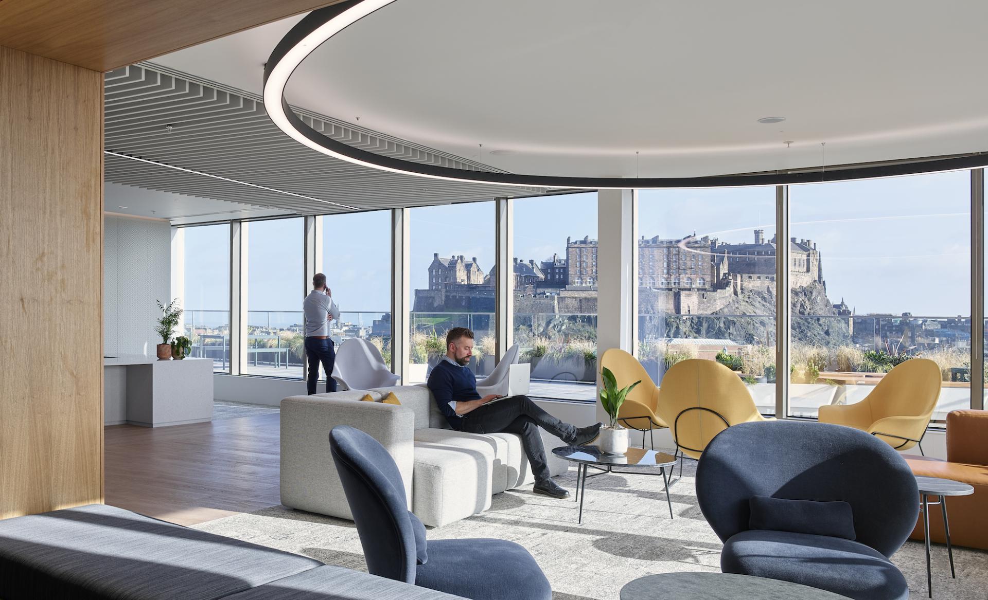 Modern workspace with panoramic views of Edinburgh, featuring stylish furniture and relaxed atmosphere, promoting a collaborative design approach.