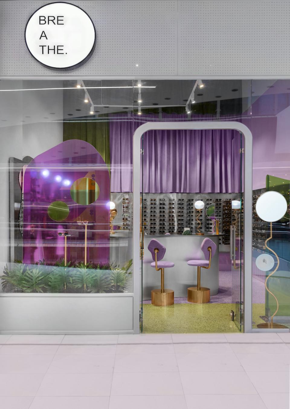Modern eyewear store Breathe in Colombia featuring vibrant purple decor and stylish display of sunglasses and frames.