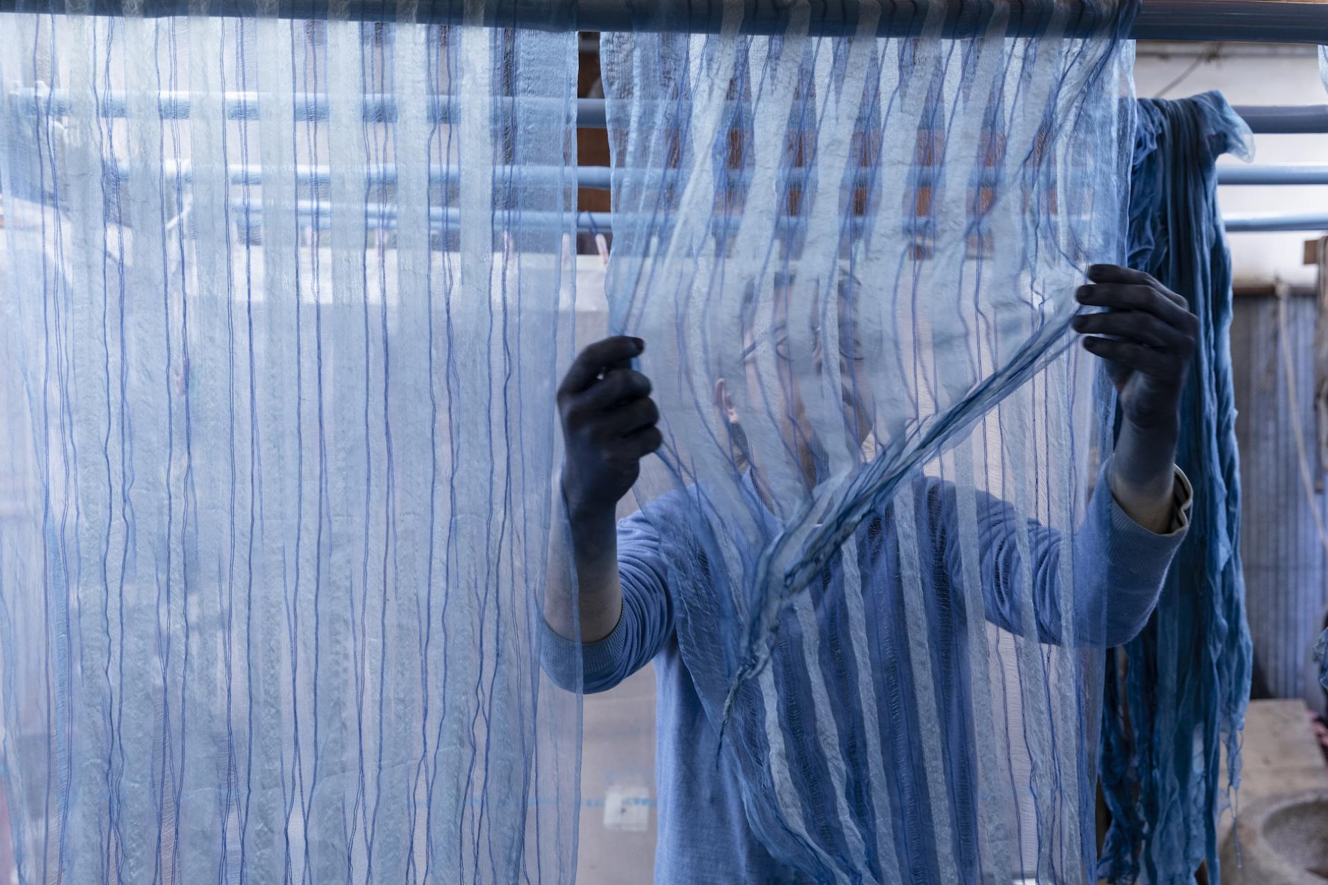Artisan showcasing natural dyeing techniques on delicate, blue-striped fabric, highlighting the beauty of Japanese color combinations.