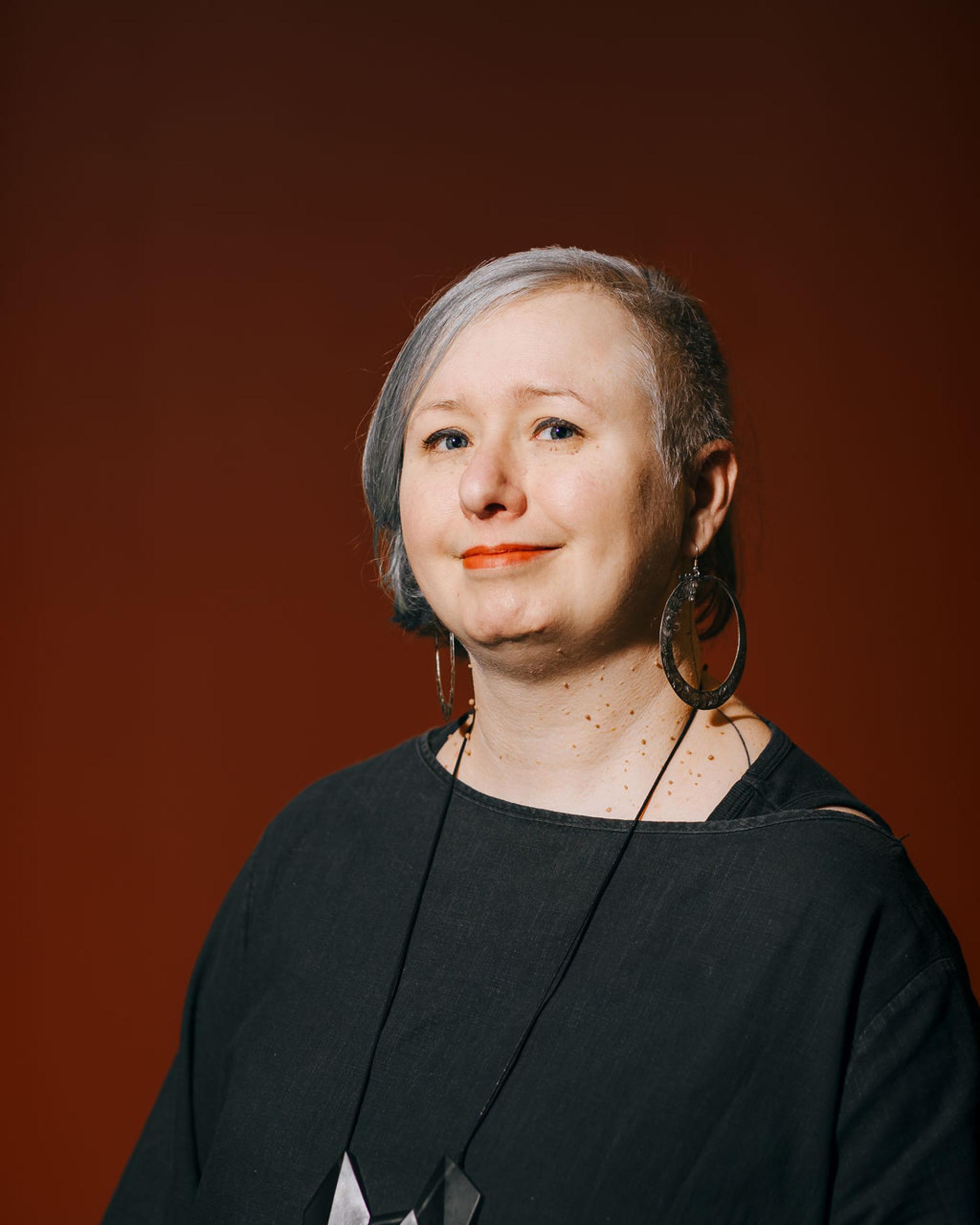 Professional-looking individual with silver hair and statement earrings, reflecting a modern approach to sustainability in biomaterials.