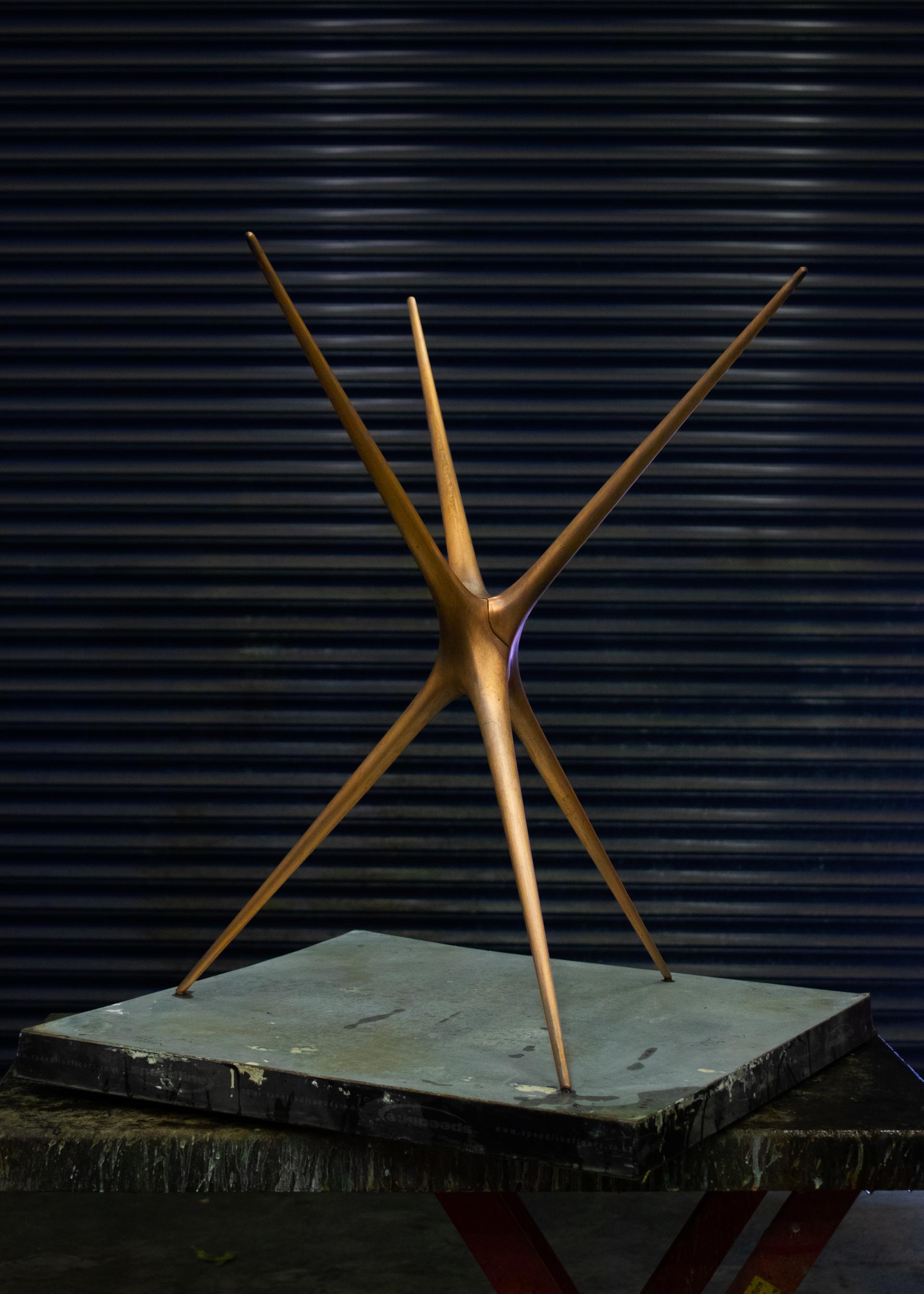 Sculptural trestle design by Brodie Neill, featuring dynamic, pointed forms atop a solid base, against a dark background.