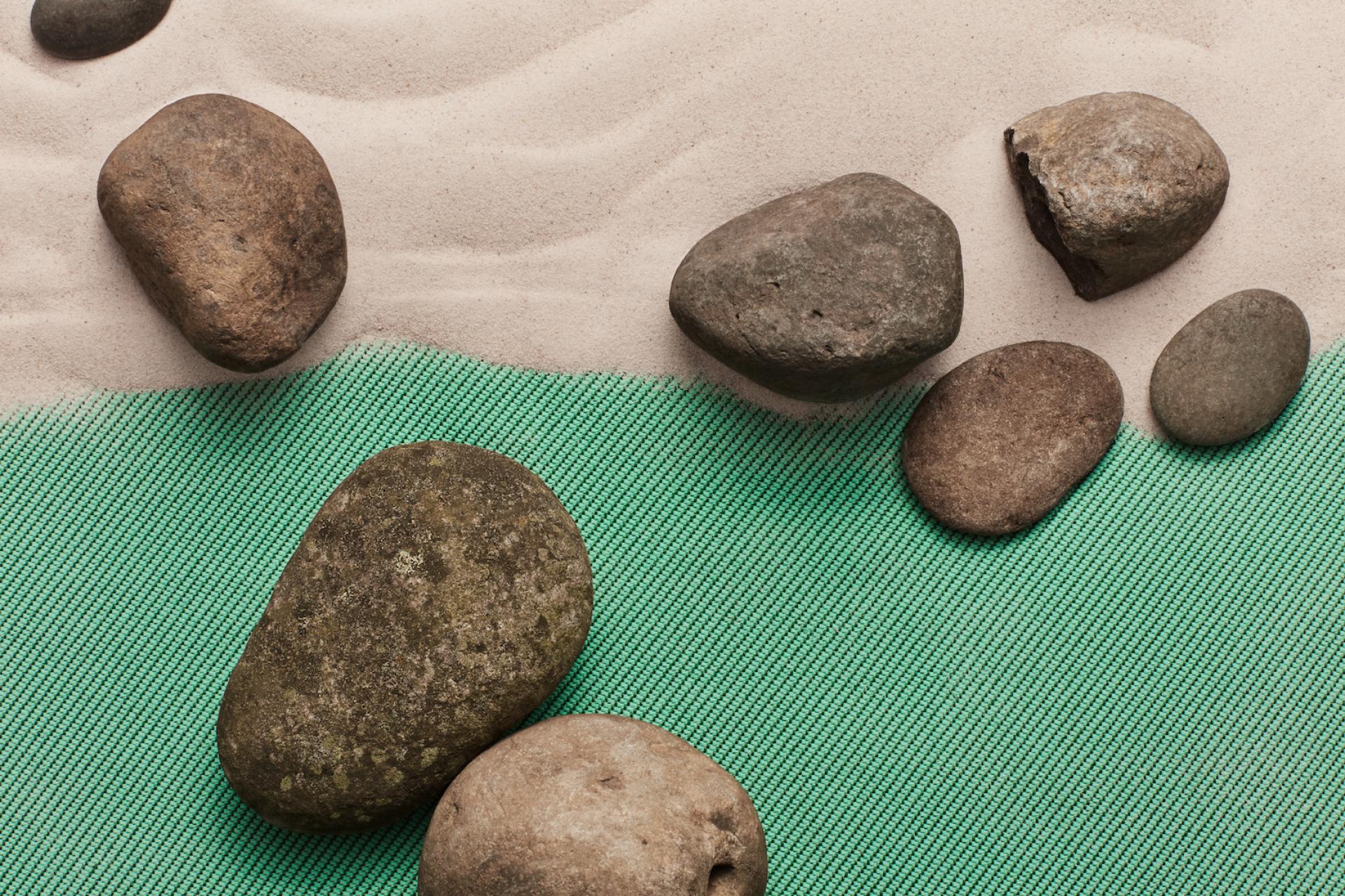 Sustainable fabric made from recycled plastic marine waste on a sandy surface with pebbles, highlighting eco-friendly design.